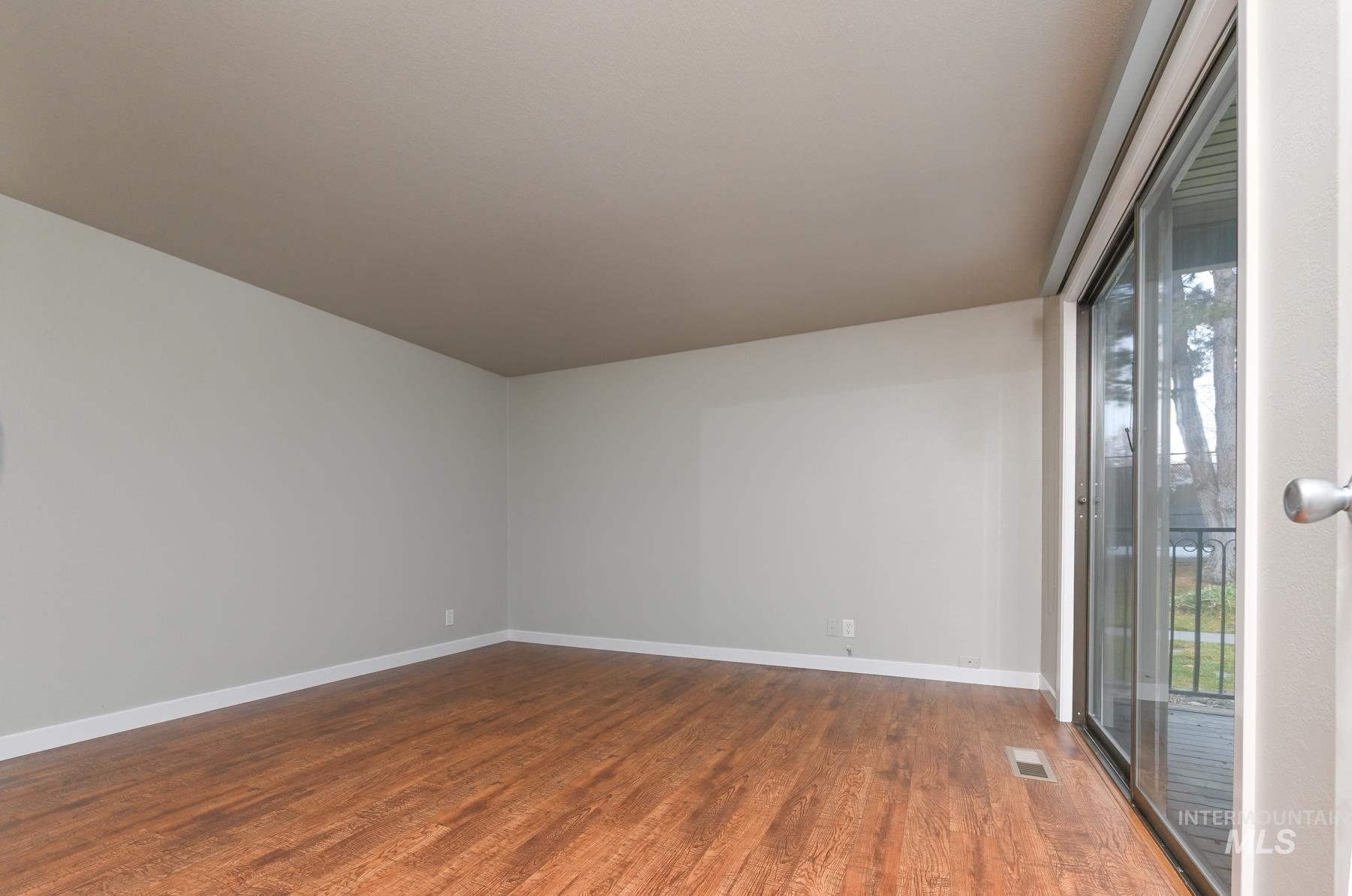 Spare room with dark wood-style floors and baseboards