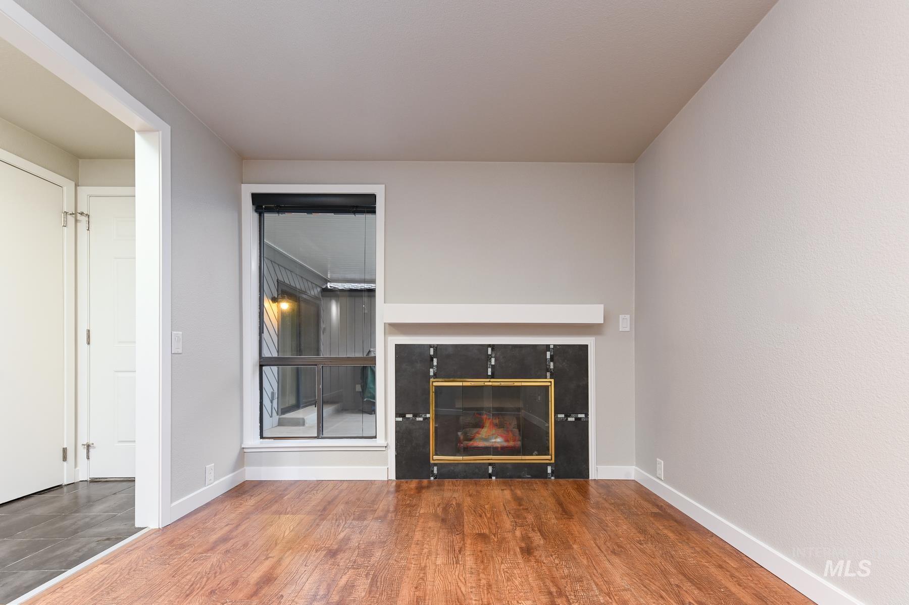 Unfurnished living room with wood finished floors and a glass covered fireplace