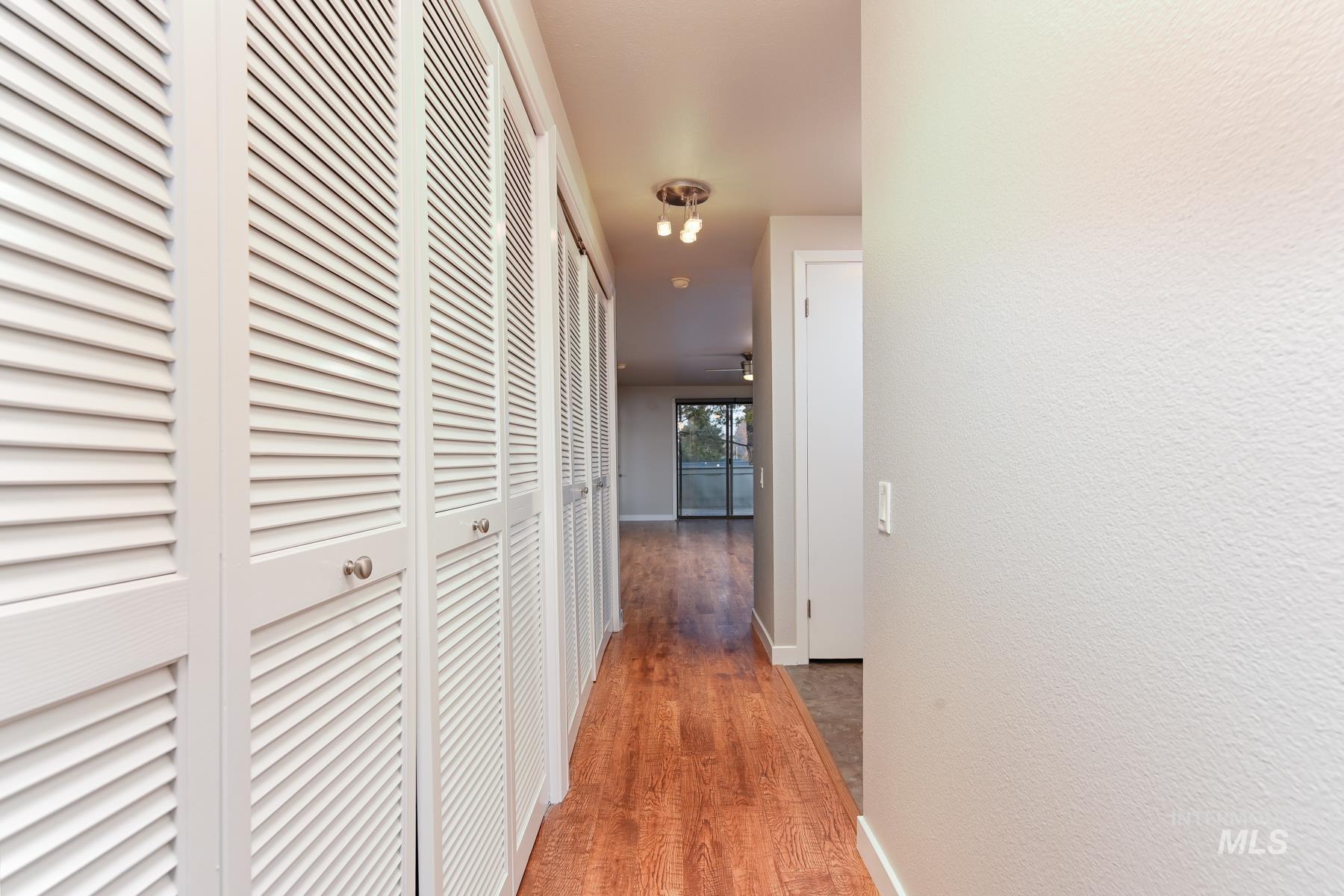 Corridor featuring light wood-style flooring and a textured wall