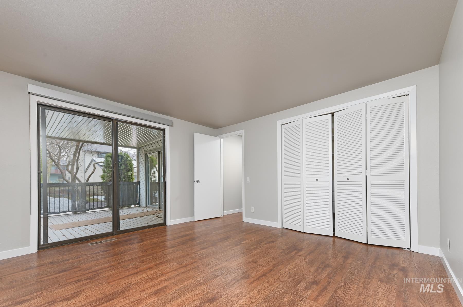 Unfurnished bedroom featuring a closet, access to exterior, and dark wood-type flooring