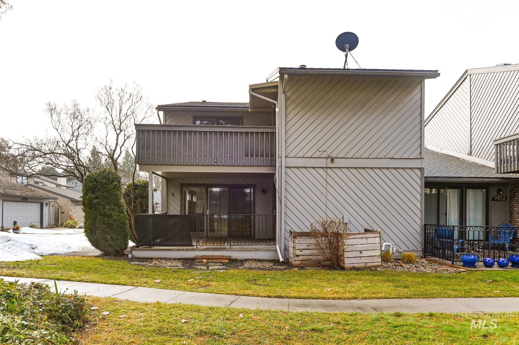 Back of house with a balcony and a lawn