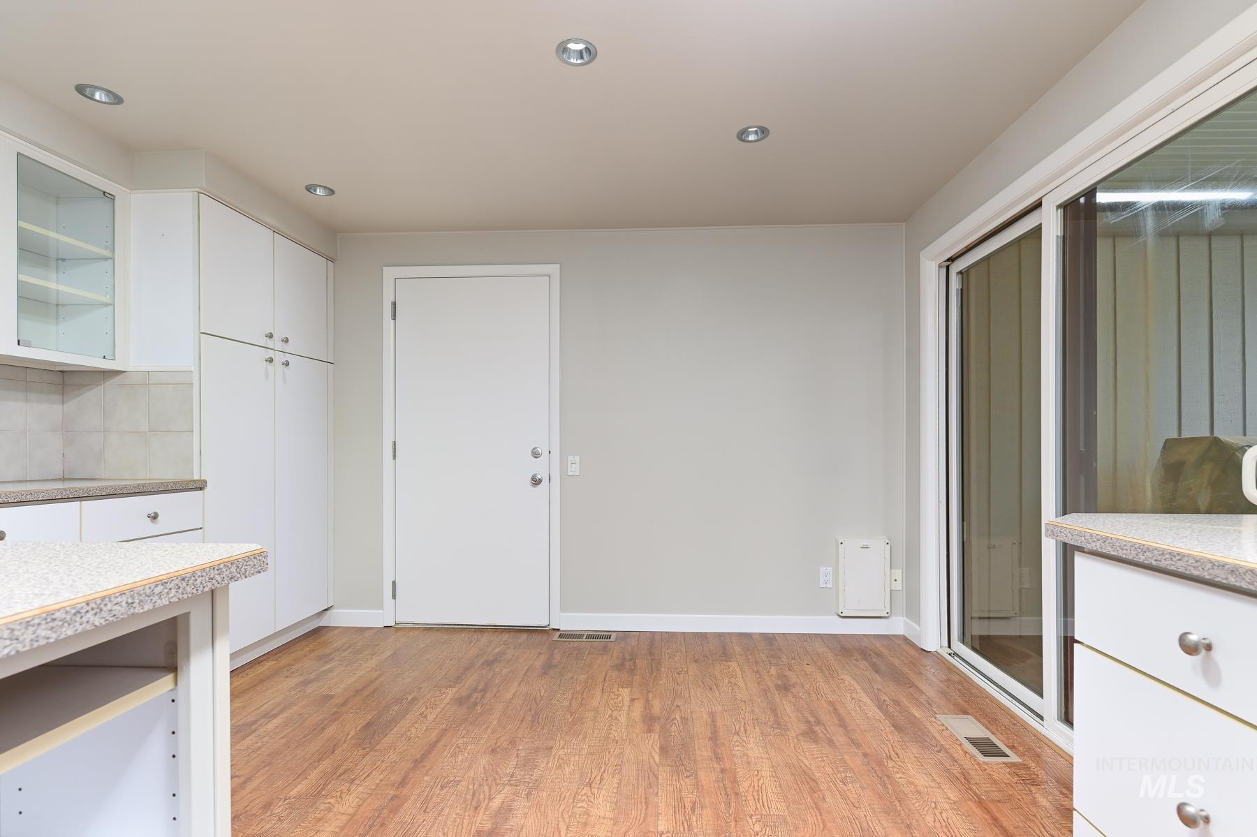 Kitchen featuring white cabinetry, light wood-style flooring, glass fronted cabinets, decorative backsplash, and recessed lighting