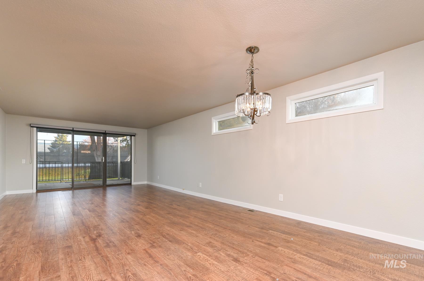 Spare room with wood finished floors and hanging lights