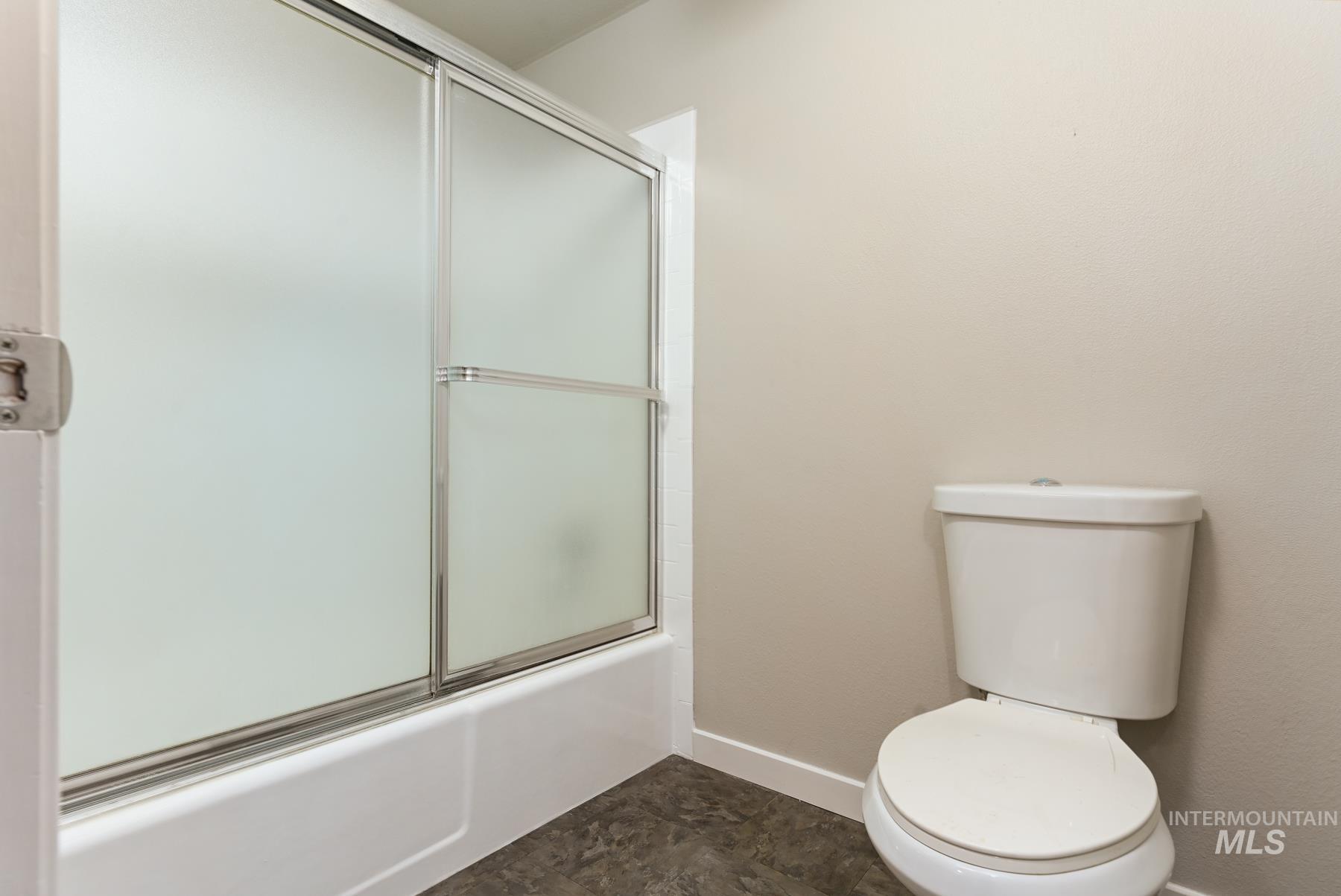 Bathroom with toilet and shower / bath combination with glass door