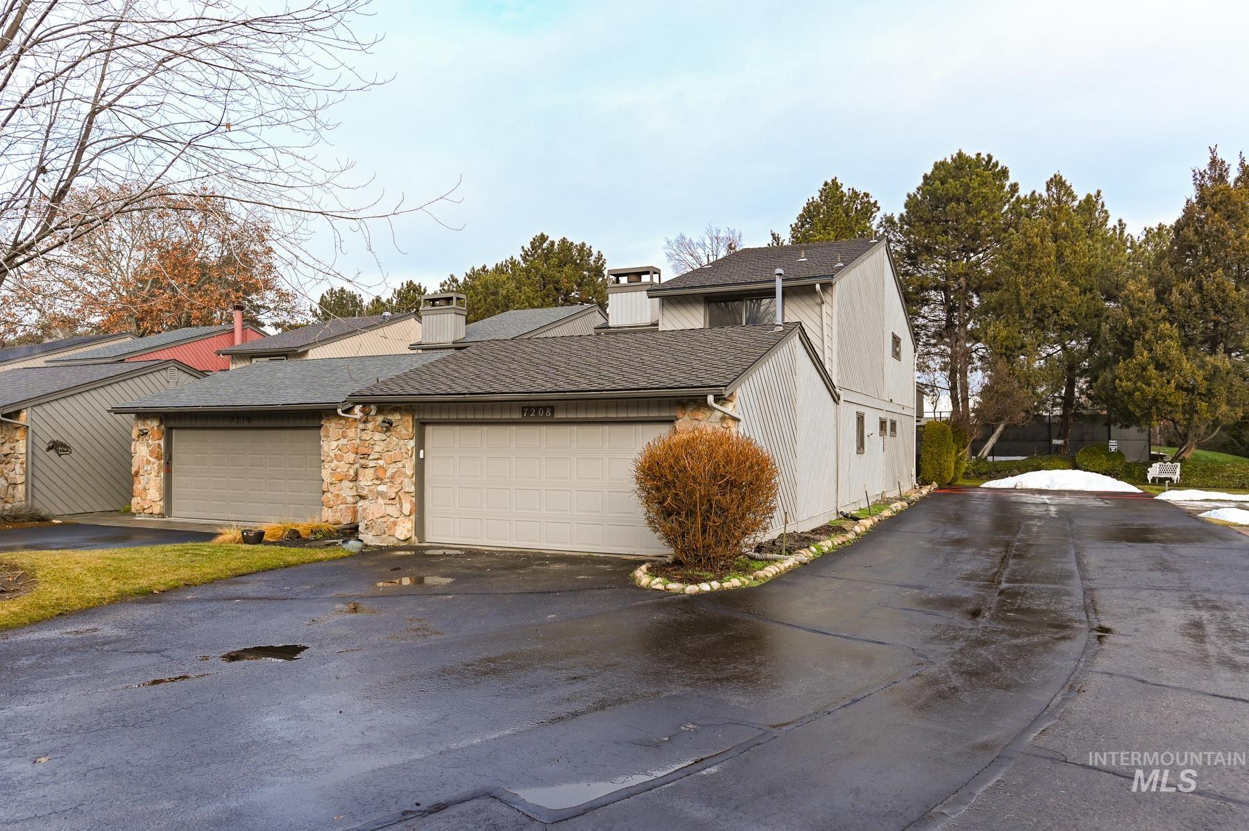 View of front of house with a chimney, roof with shingles, driveway, a garage, and stone siding