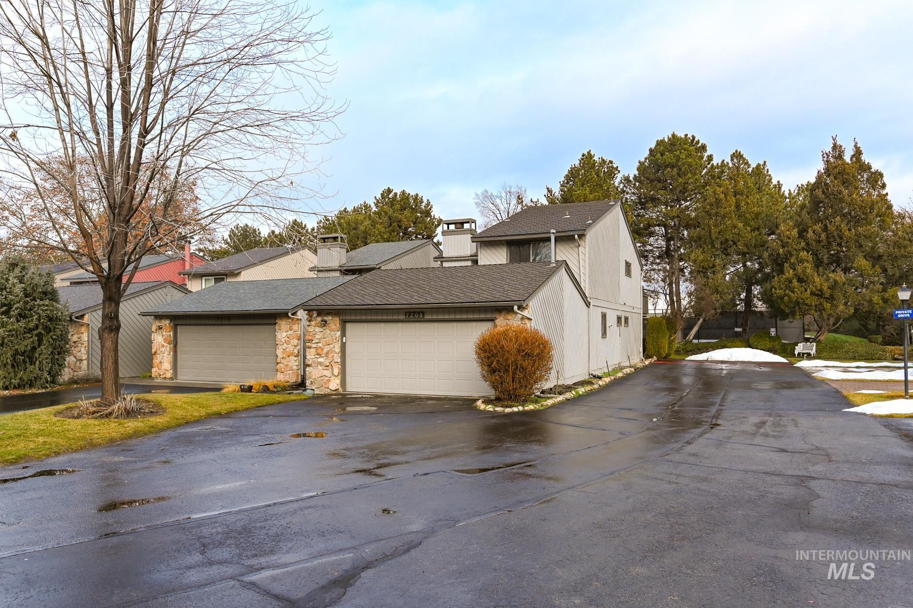 View of home's exterior with a chimney, stone siding, driveway, roof with shingles, and a garage