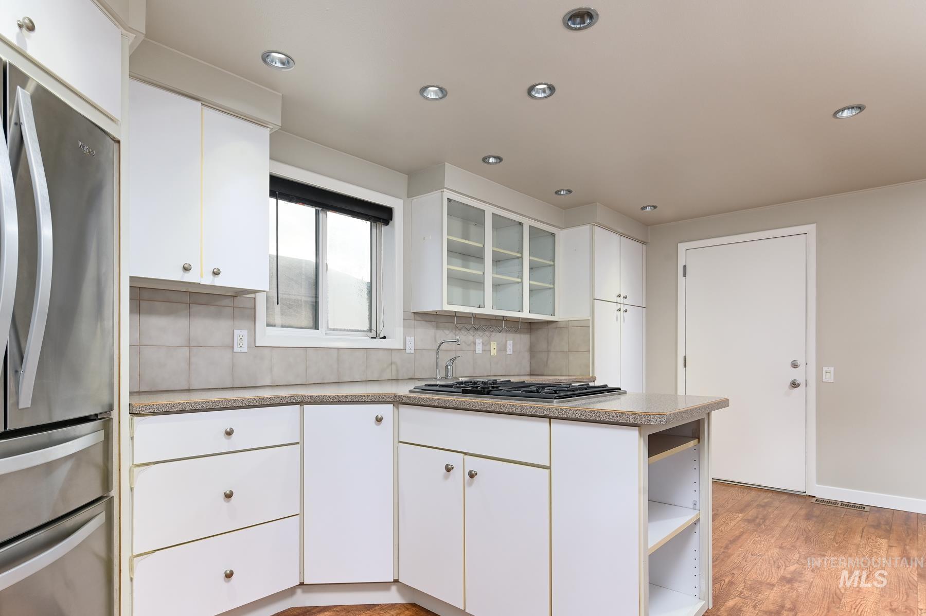 Kitchen featuring glass fronted cabinets, stainless steel appliances, white cabinets, tasteful backsplash, and open shelves