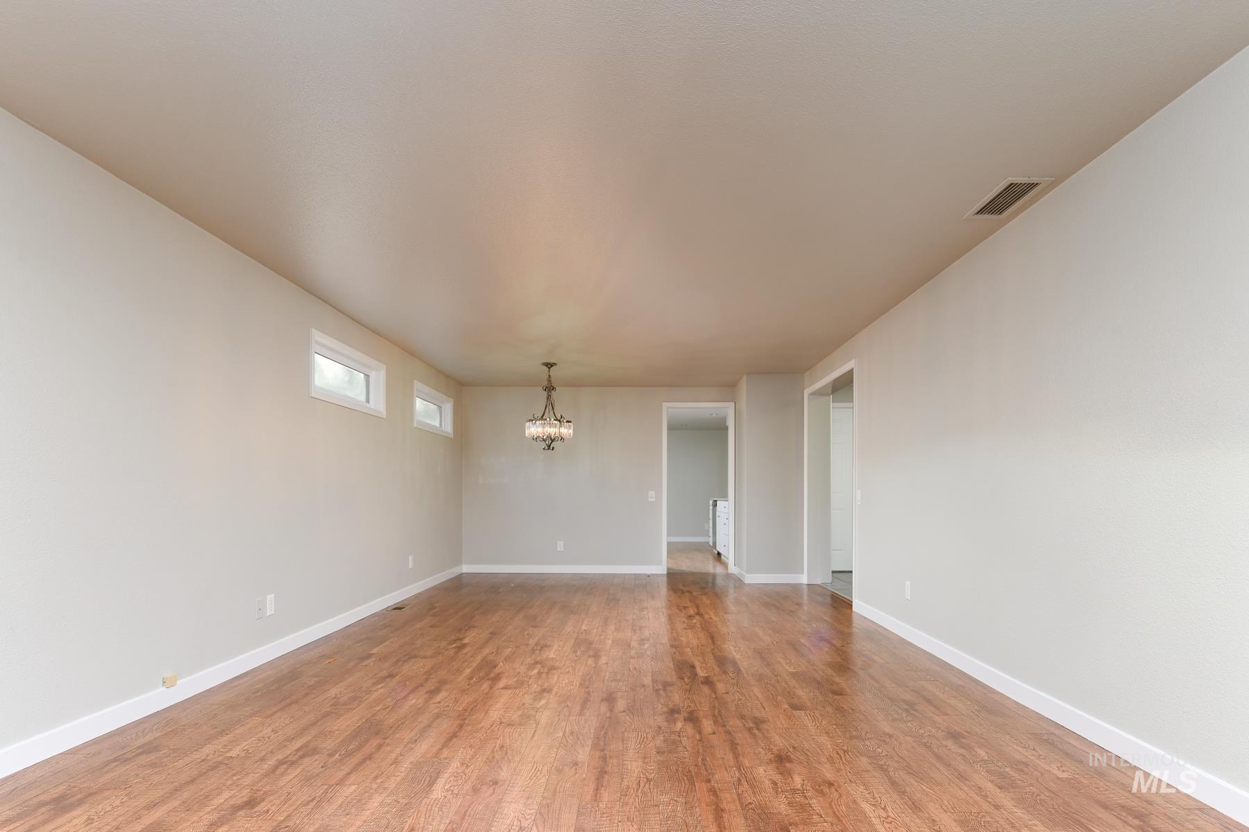 Unfurnished room featuring wood finished floors and a chandelier