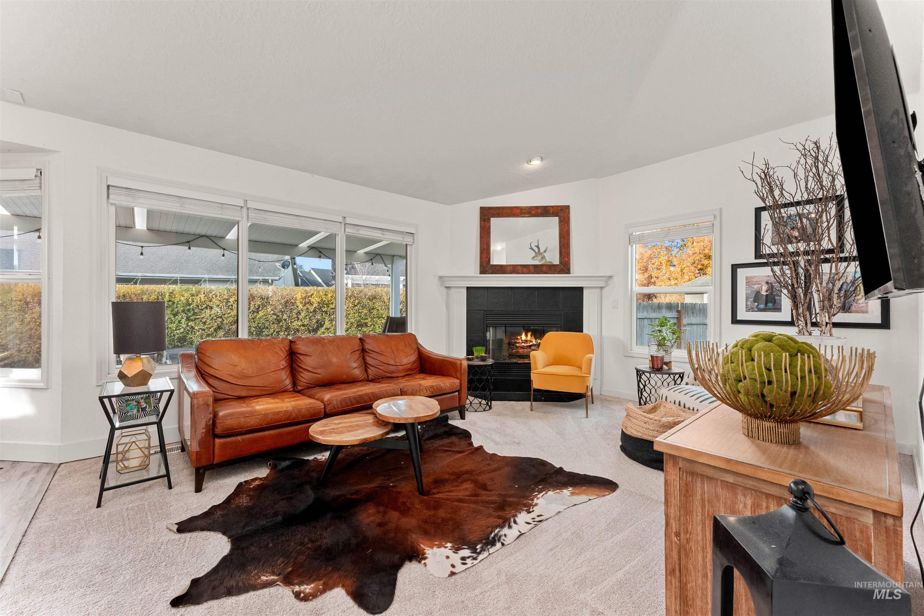 Living room with a fireplace, light colored carpet, and vaulted ceiling