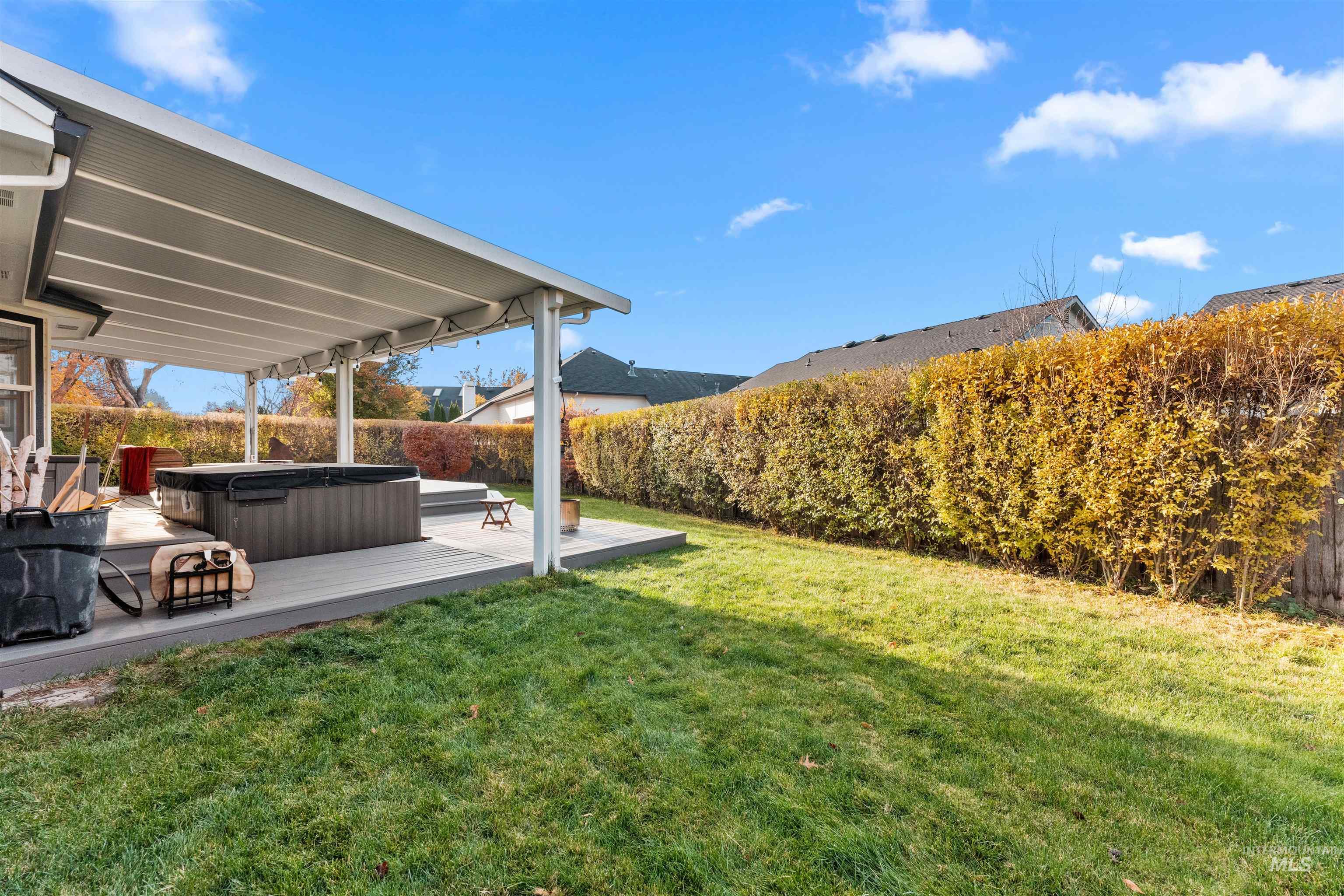 Fenced backyard featuring a hot tub and a deck