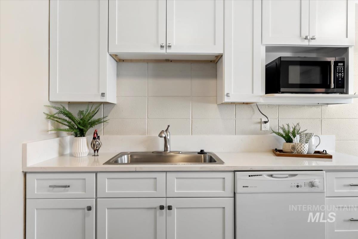 Kitchen featuring dishwasher, white cabinets, and decorative backsplash