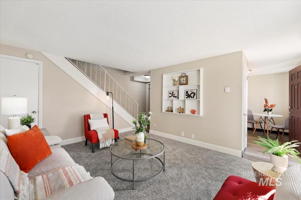 Living area with a textured ceiling, stairs, and carpet floors