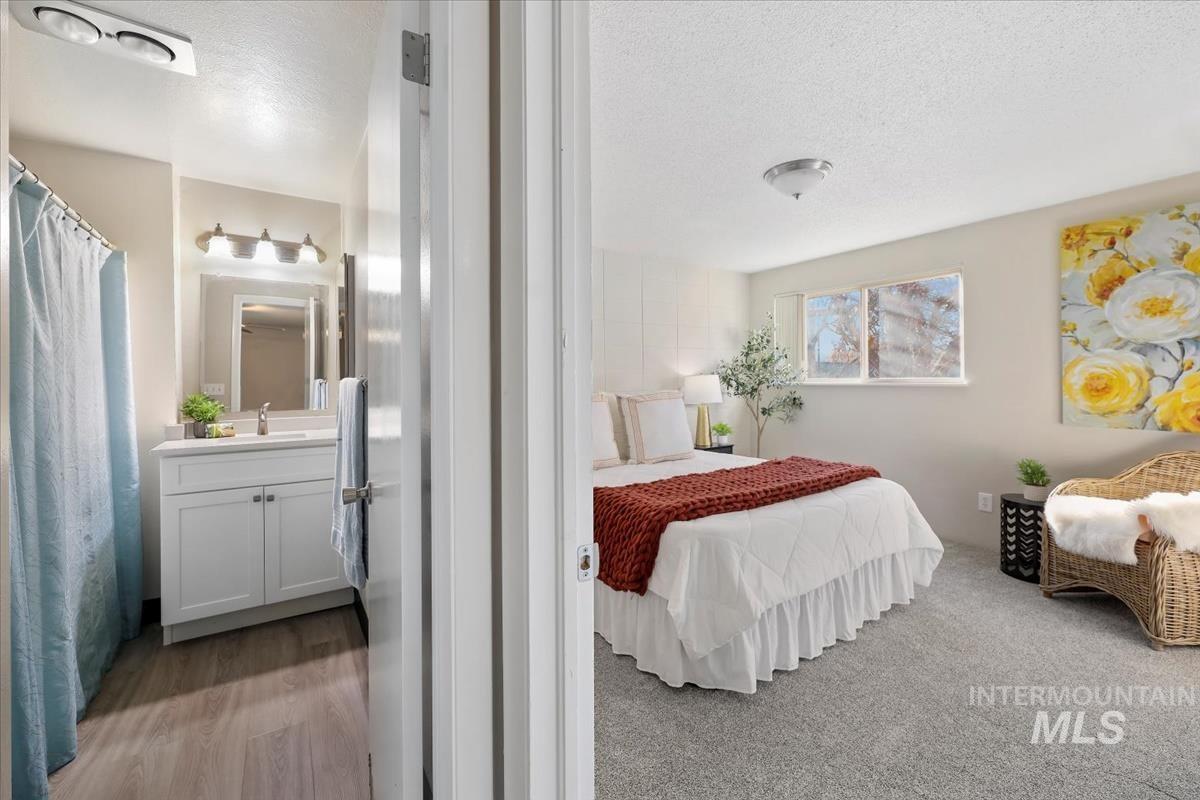 Bedroom featuring a textured ceiling, ensuite bath, and light wood-style flooring