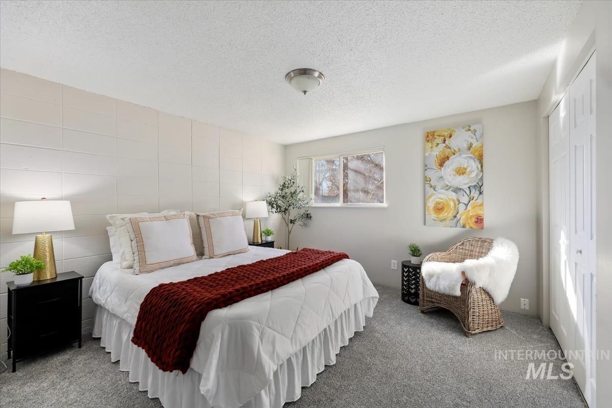 Carpeted bedroom with a textured ceiling and a closet