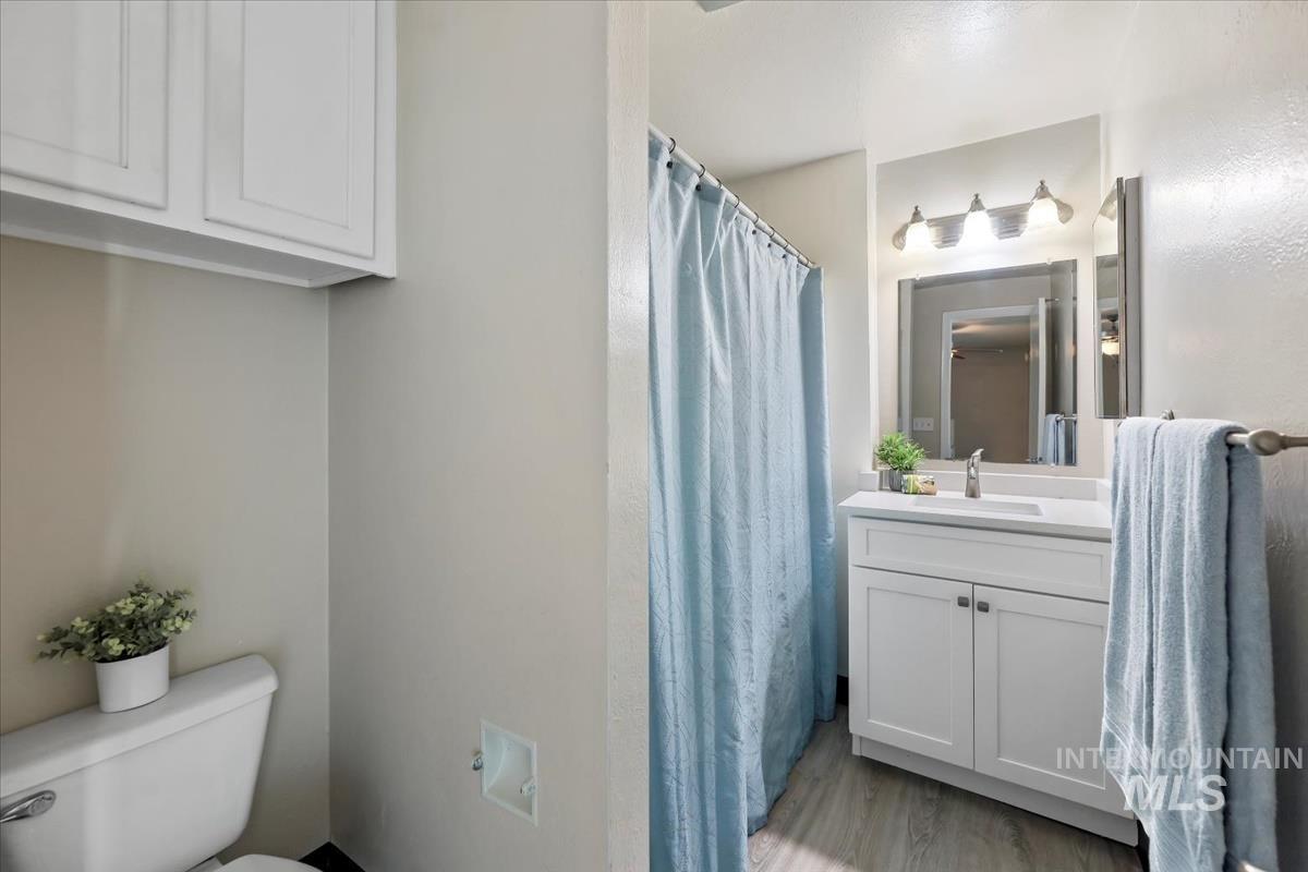 Full bath with vanity, a shower with curtain, and light wood-type flooring