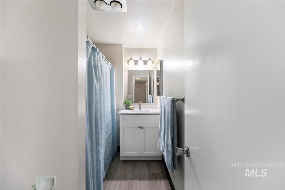 Bathroom featuring vanity, curtained shower, and dark wood-style floors