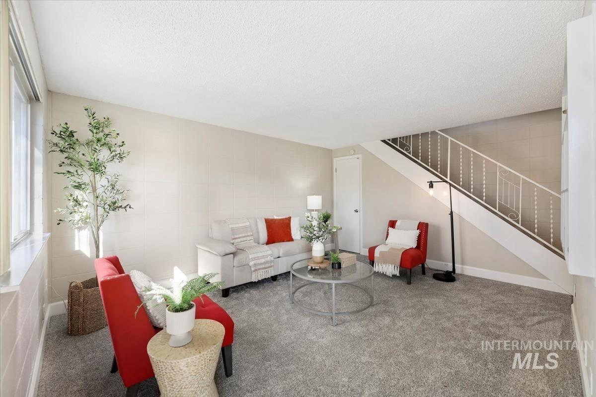 Carpeted living room featuring stairway and a textured ceiling
