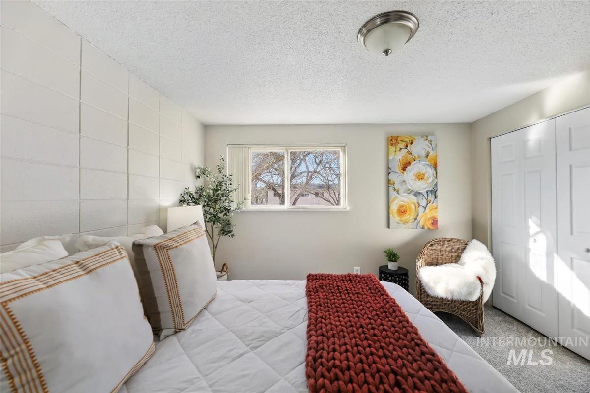 Carpeted bedroom featuring a textured ceiling and a closet