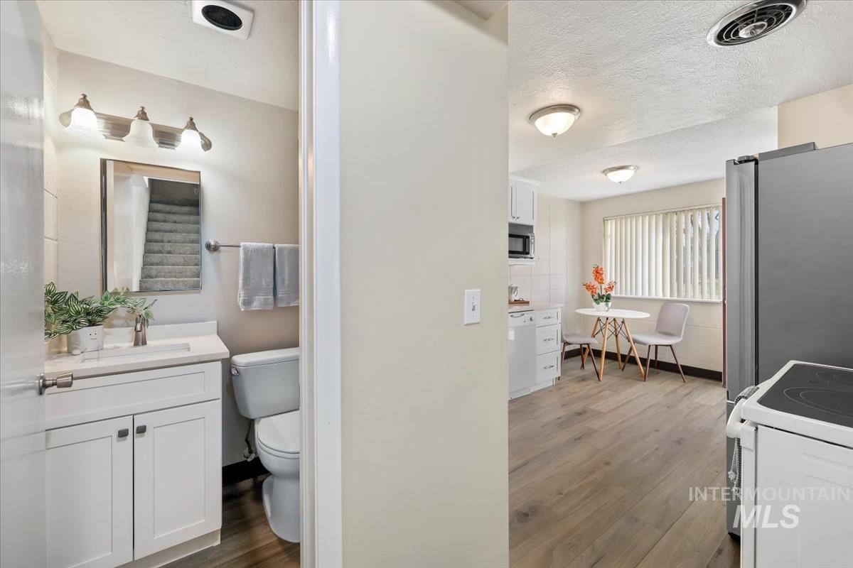 Bathroom with vanity, light wood-type flooring, and a textured ceiling