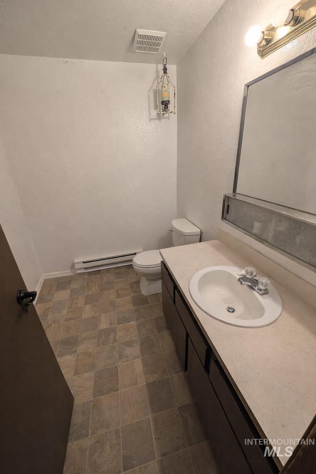 Half bathroom featuring vanity, a baseboard radiator, a textured wall, and a textured ceiling