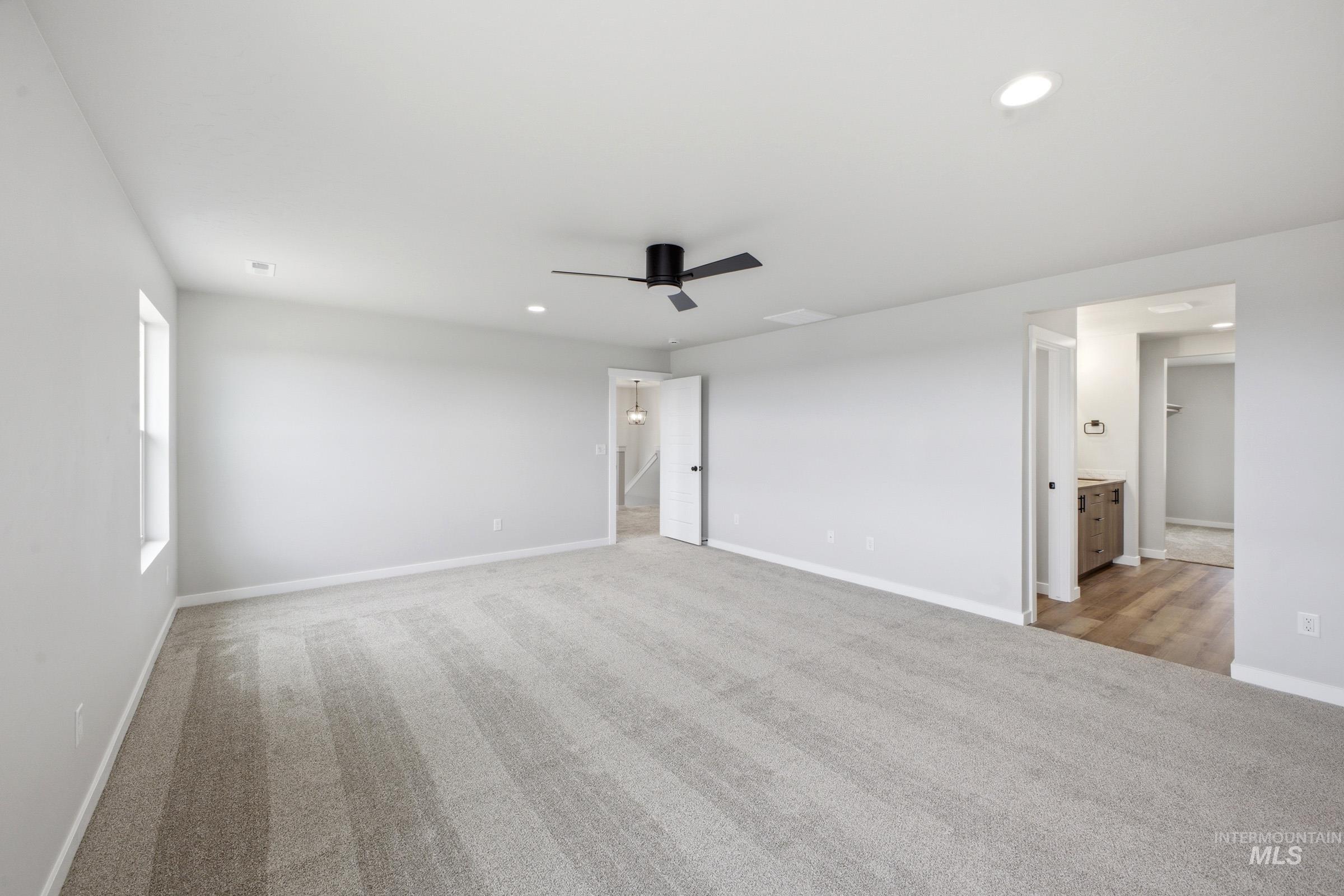 Spacious room featuring light gray carpeting and a white ceiling with recessed lighting