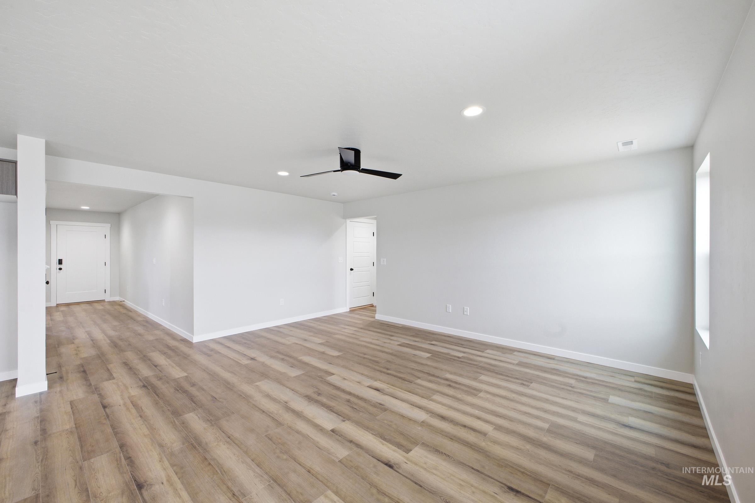Spacious room featuring wood-finish flooring, light gray walls, and recessed lighting