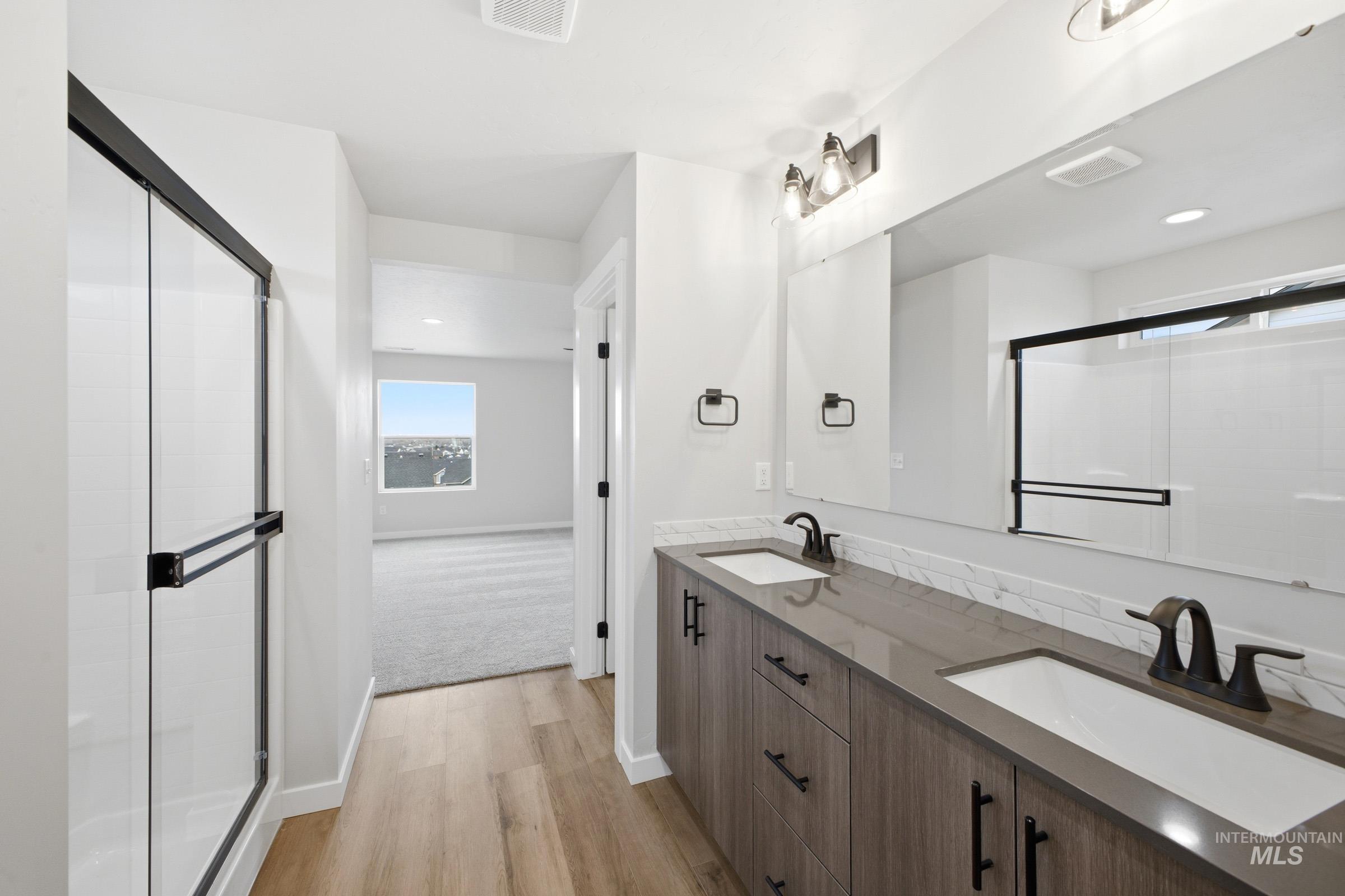 Bathroom vanity featuring dual undermount sinks, wood-finish cabinetry, and dark hardware