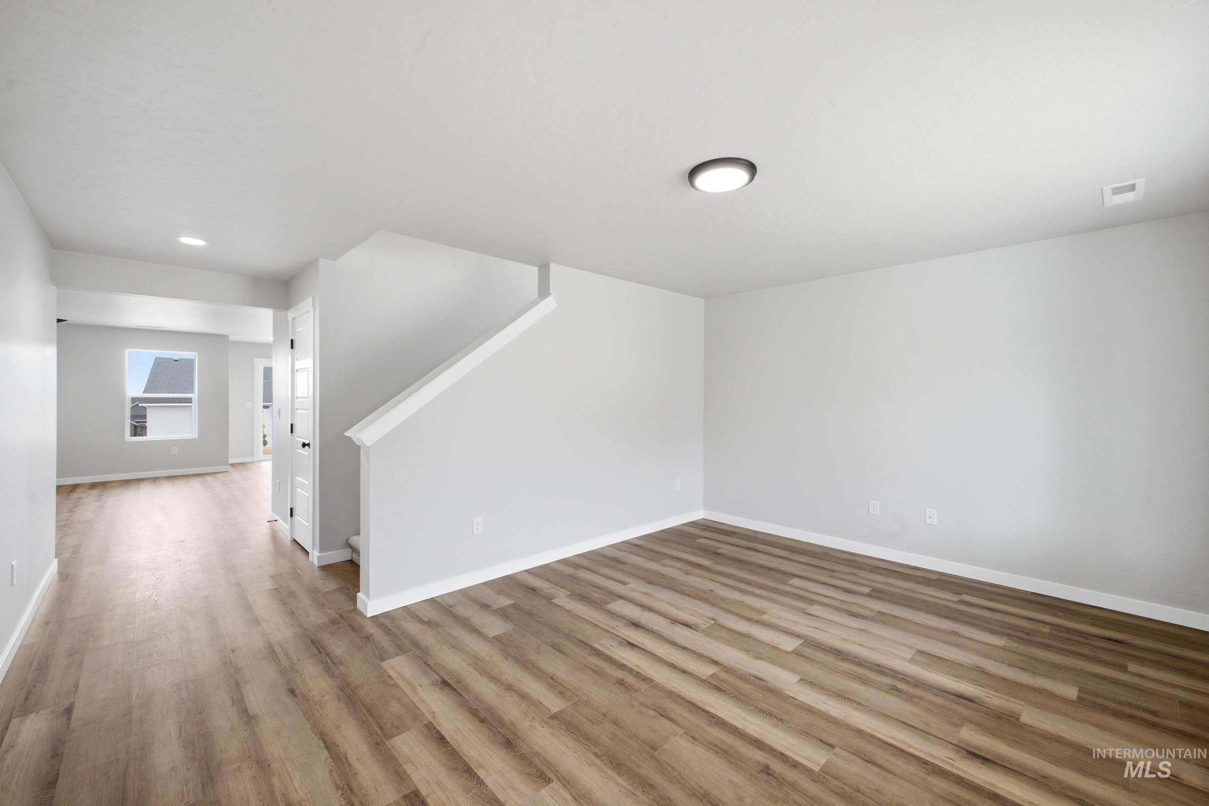 Open-concept interior featuring wood-finish flooring, light gray walls, white trim, and recessed lighting