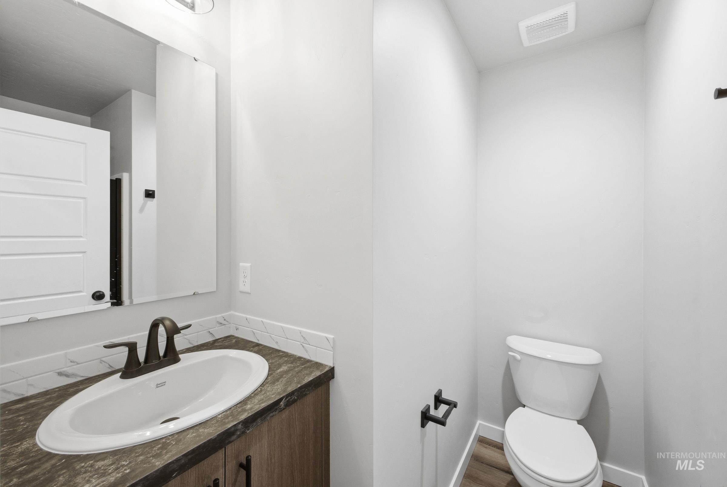 Bathroom featuring a dark wood-finish vanity with an oval sink, bronze-finish faucet, and coordinating dark countertop