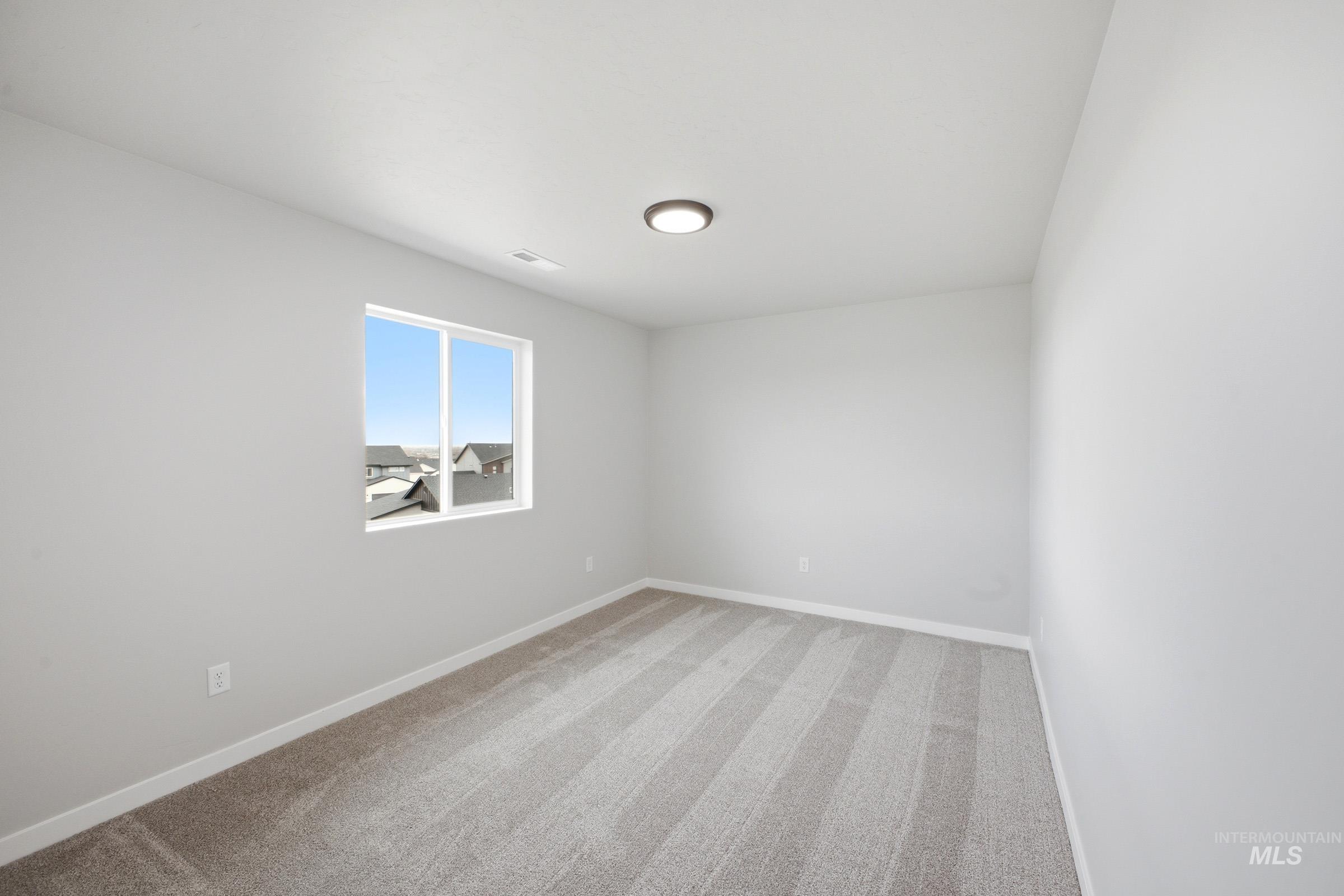 Room featuring light gray carpet with stripe patterns, white baseboards, and neutral wall paint