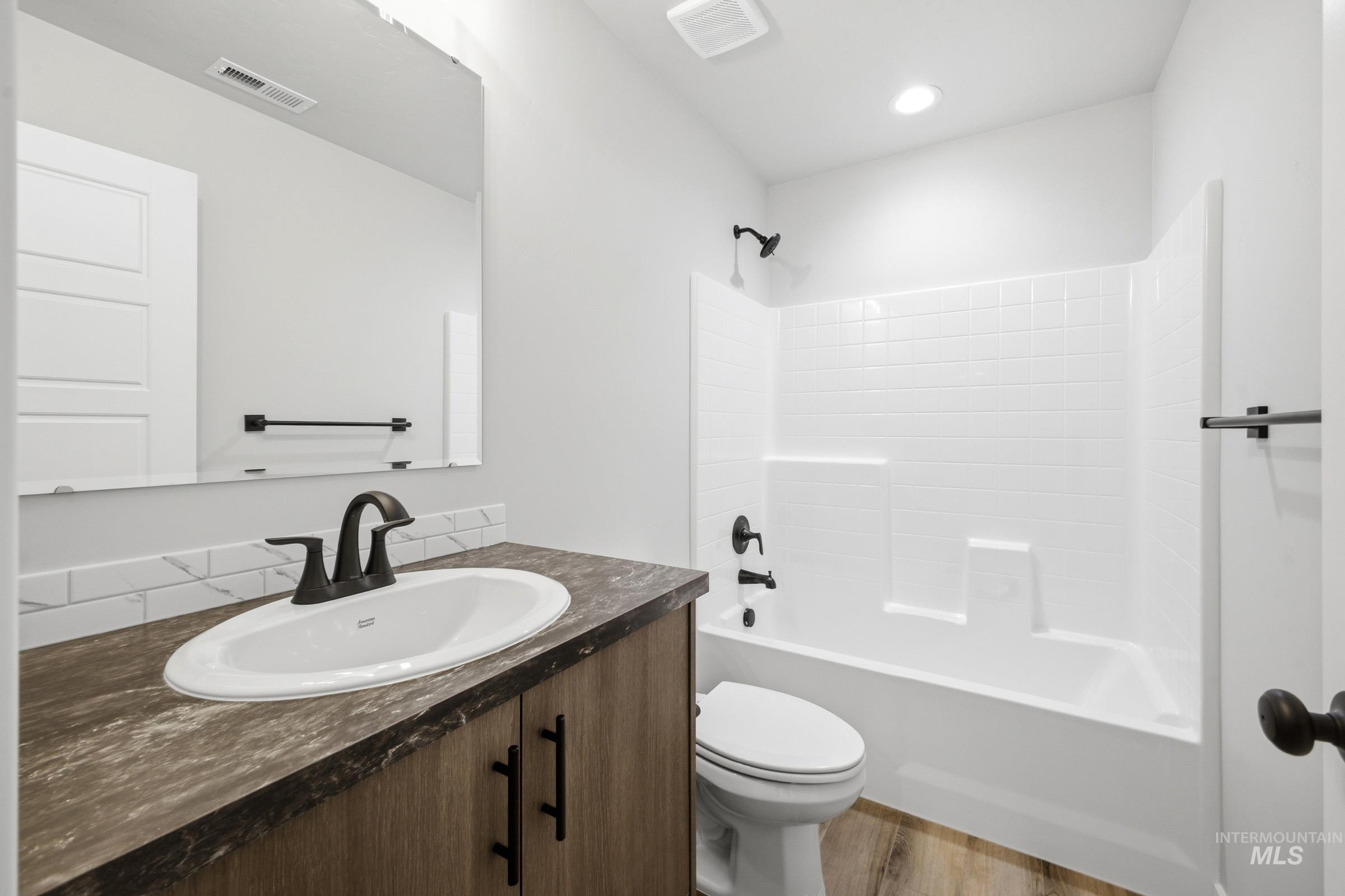 Bathroom featuring a vanity with dark wood-finish cabinetry, a white oval sink, and a dark countertop