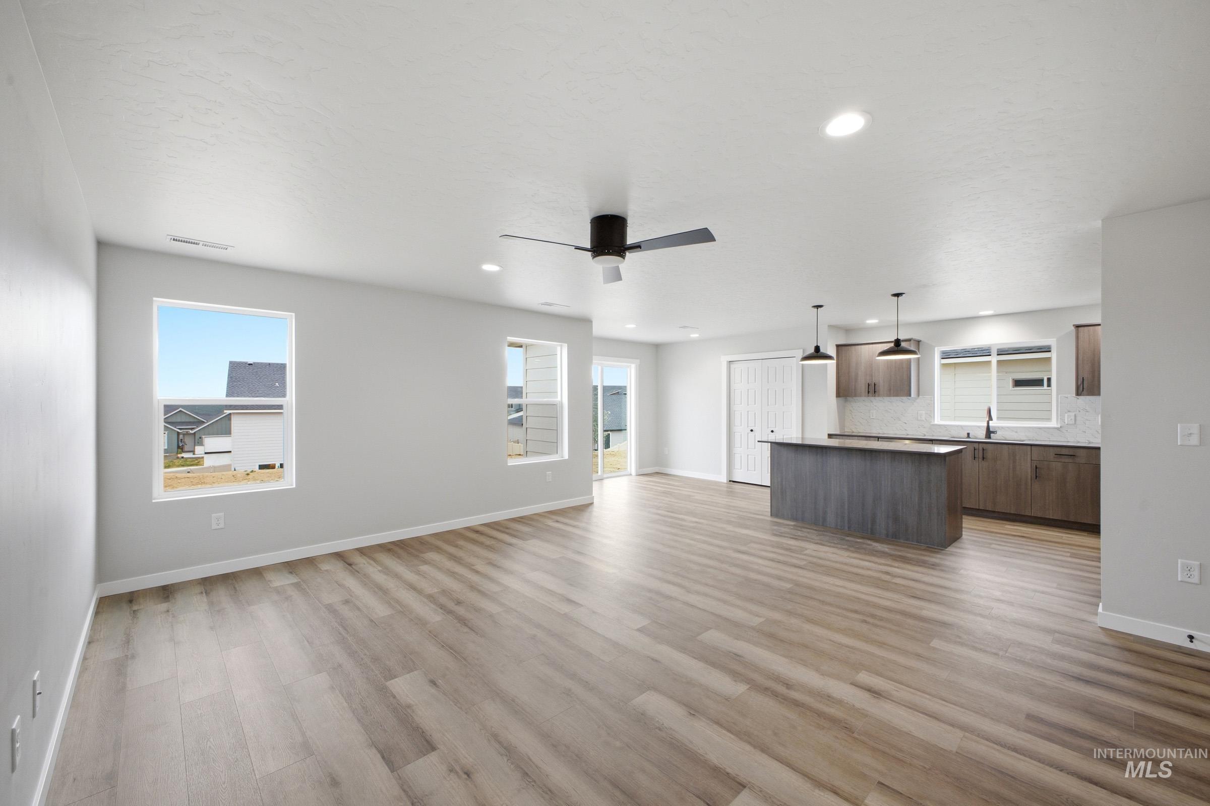 Open-concept living space featuring wood-finish flooring, recessed lighting, and a contemporary ceiling fan