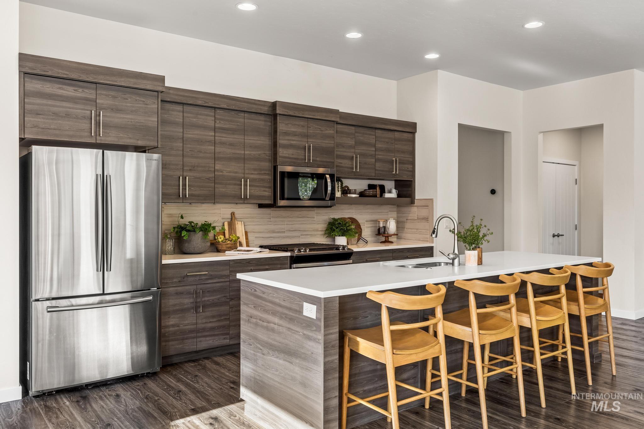 Kitchen with appliances with stainless steel finishes, backsplash, recessed lighting, a breakfast bar, and dark wood finished floors