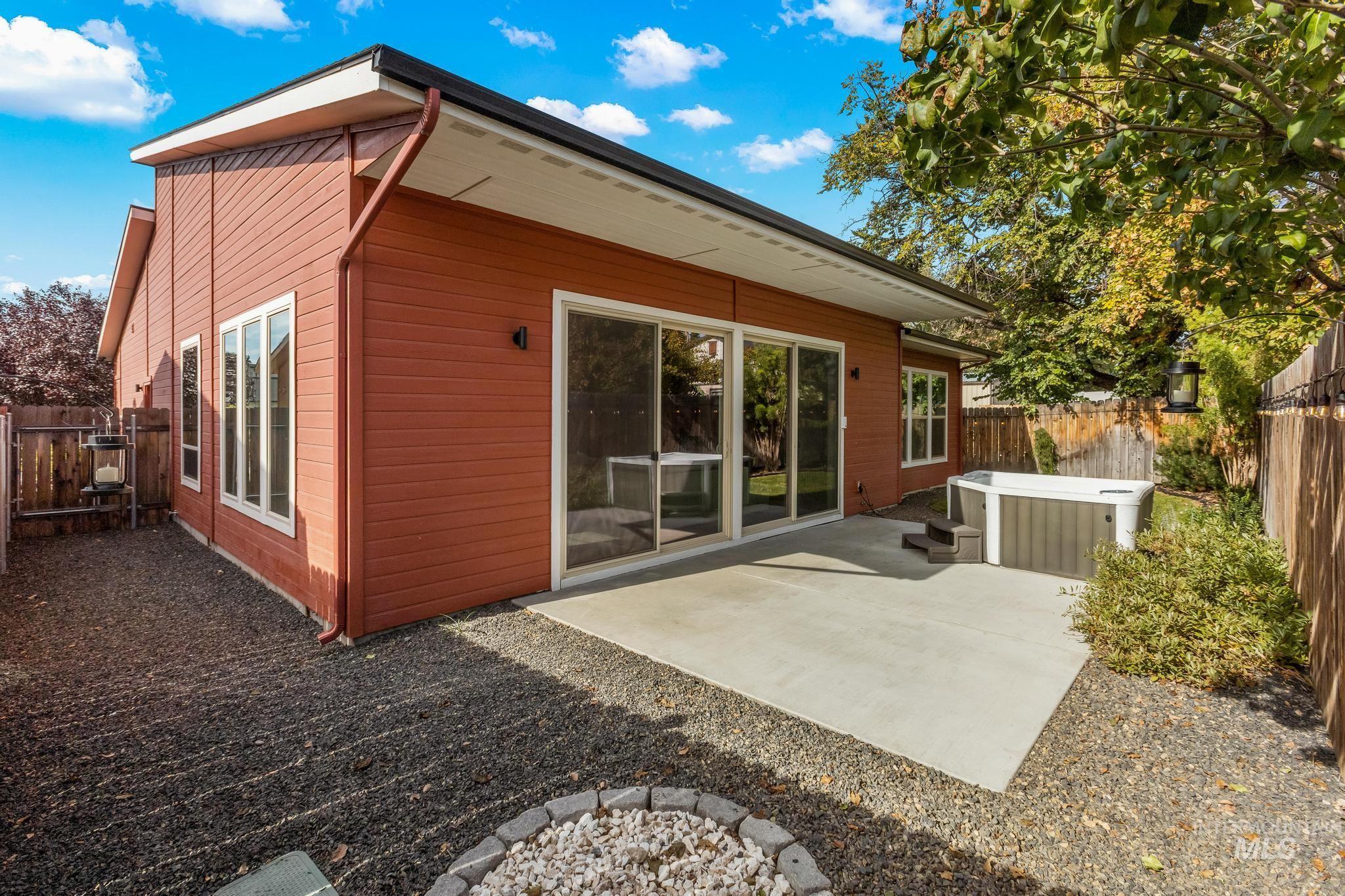 Back of property featuring a fenced backyard, a hot tub, a patio, and a fire pit