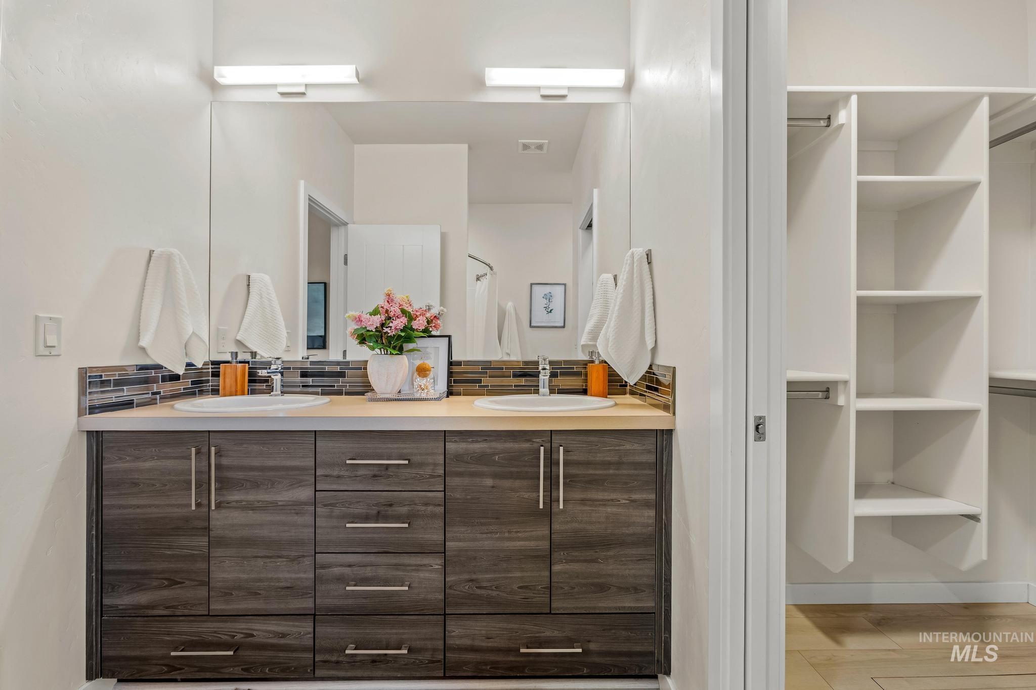 Full bathroom with backsplash, double vanity, and a closet