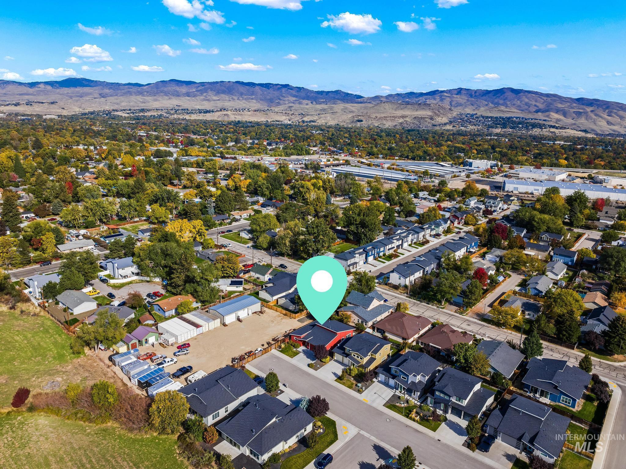 Aerial view of property and surrounding area featuring mountains and nearby suburban area