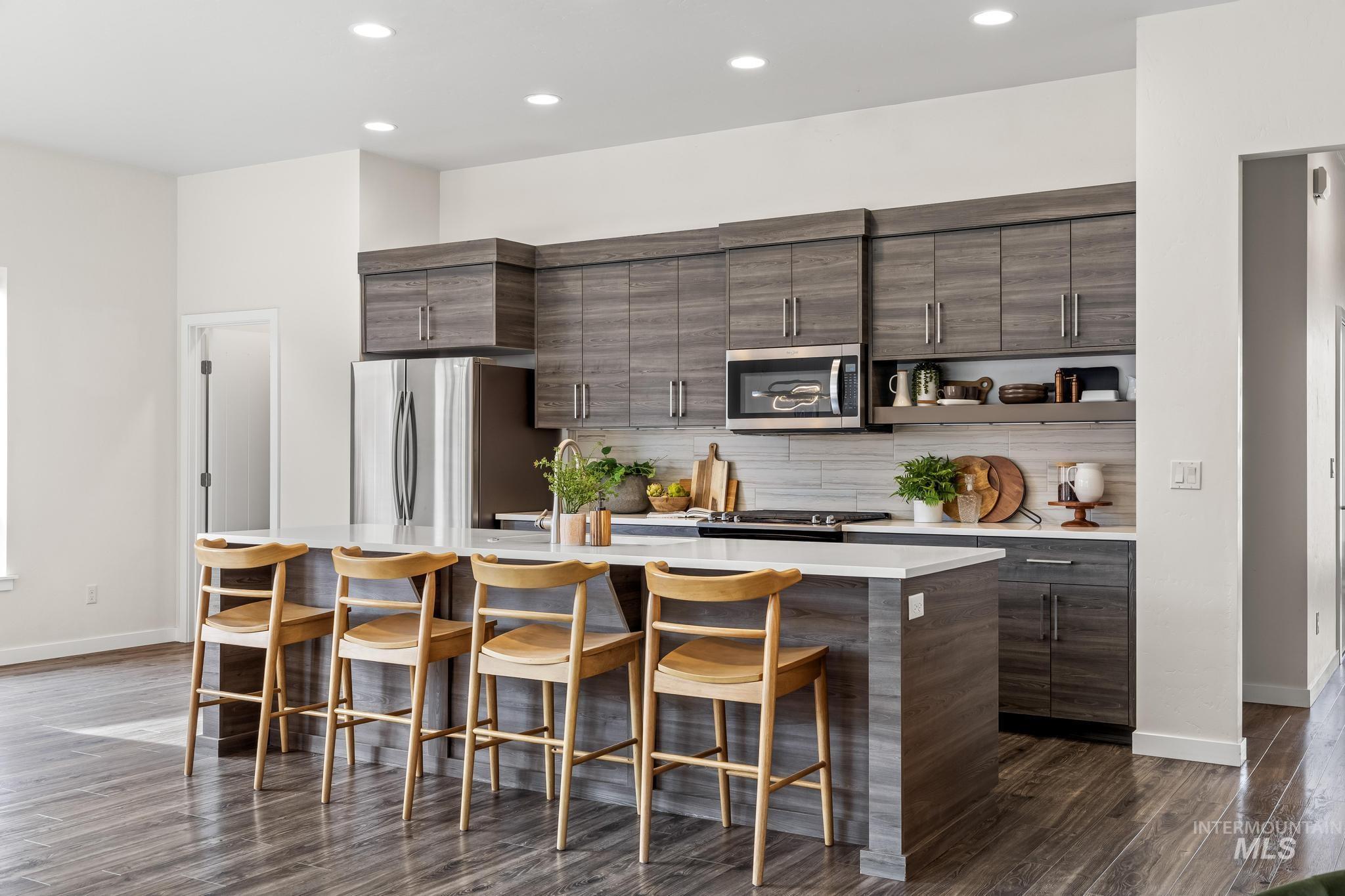 Kitchen featuring dark brown cabinets, a breakfast bar, a kitchen island with sink, dark wood-style floors, and recessed lighting