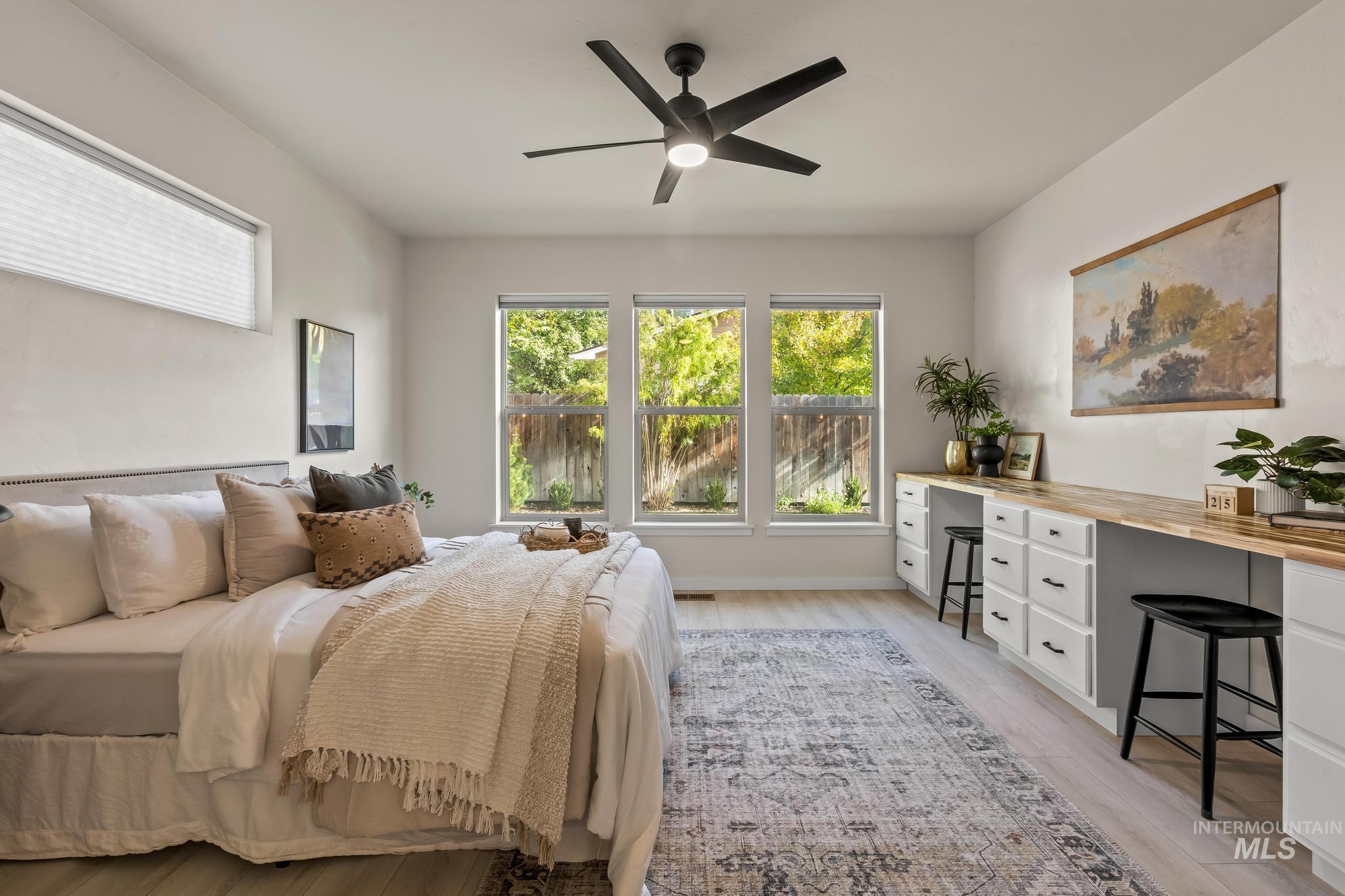 Bedroom featuring light wood finished floors, a ceiling fan, and a desk