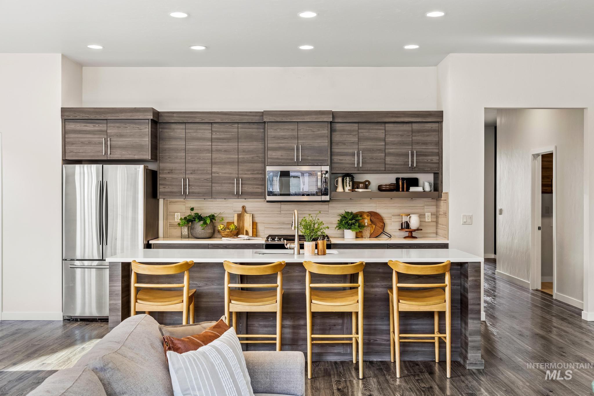 Bar area with dark brown cabinets, tasteful backsplash, stainless steel appliances, recessed lighting, and modern cabinets
