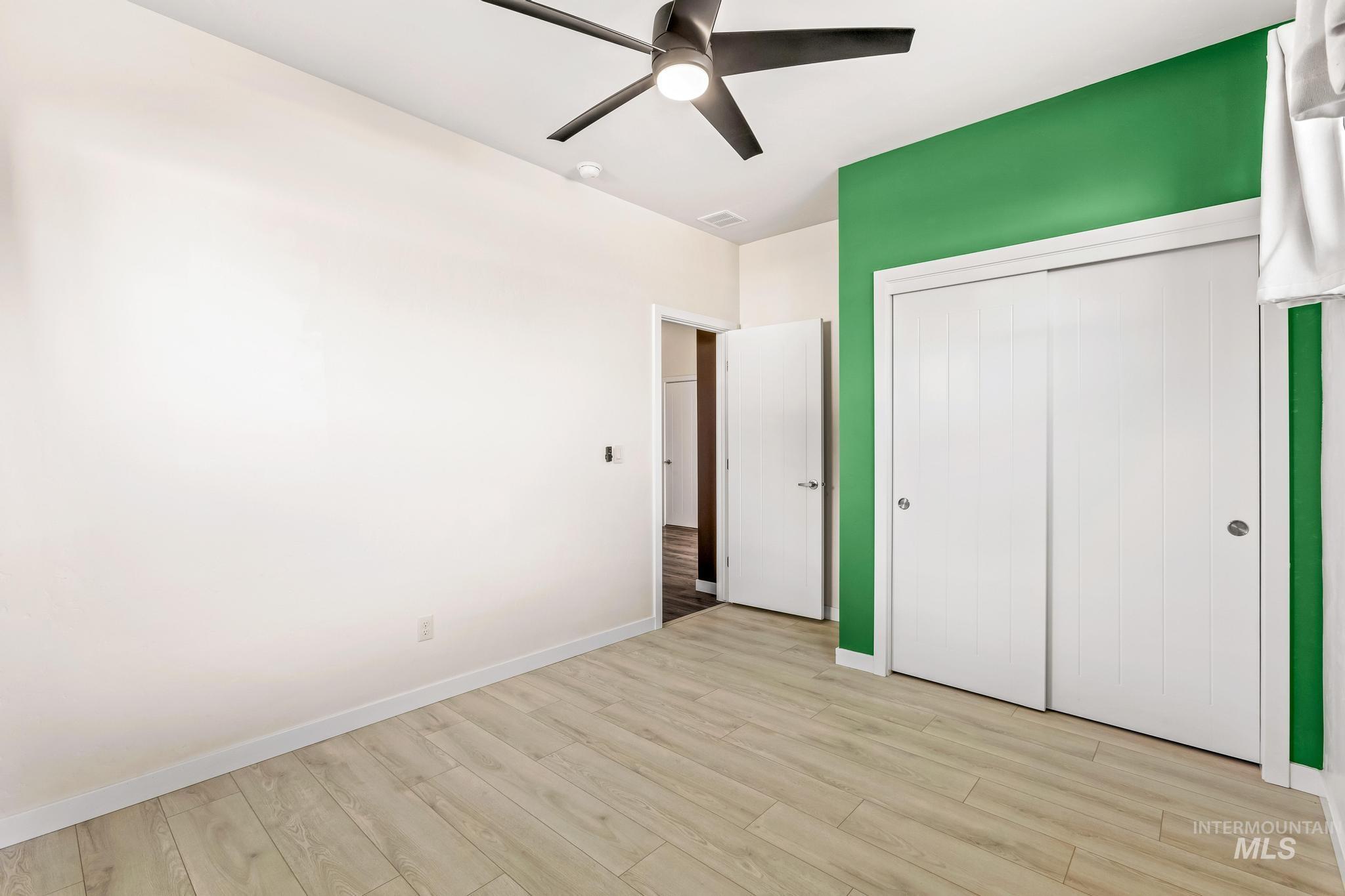 Unfurnished bedroom with light wood finished floors, a ceiling fan, and a closet