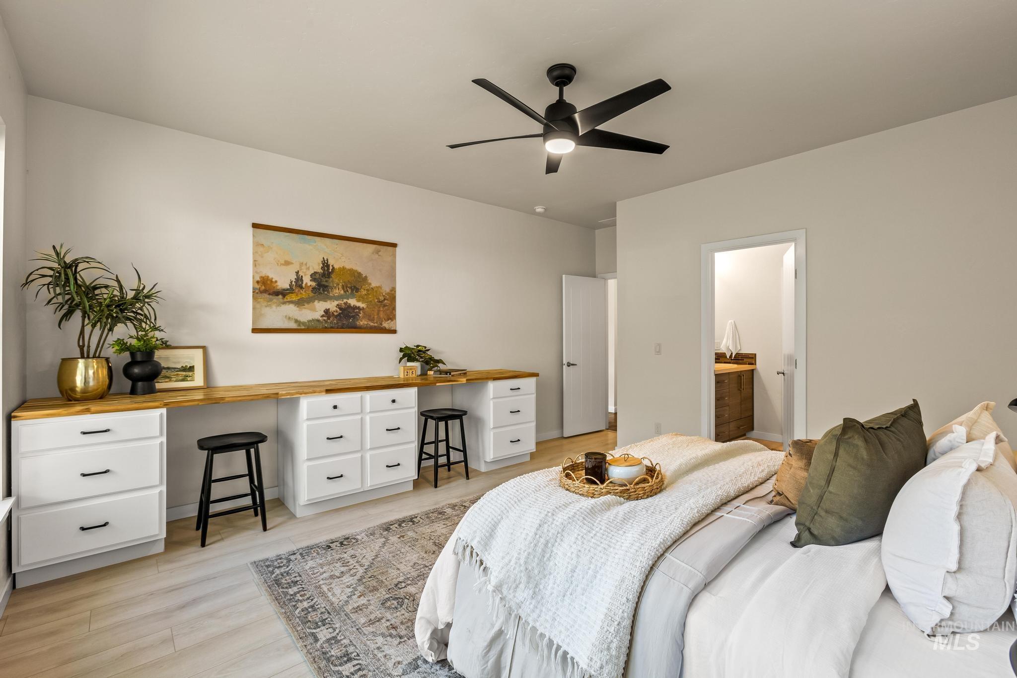 Bedroom featuring light wood-type flooring, ceiling fan, built in desk, and connected bathroom
