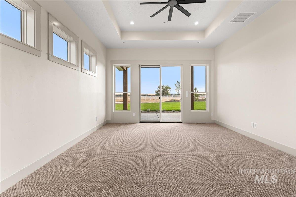 Carpeted empty room featuring a tray ceiling, ceiling fan, and recessed lighting