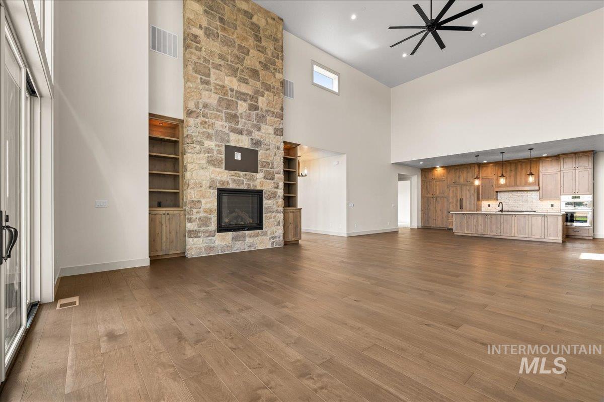 Unfurnished living room featuring a fireplace, dark wood finished floors, and a high ceiling