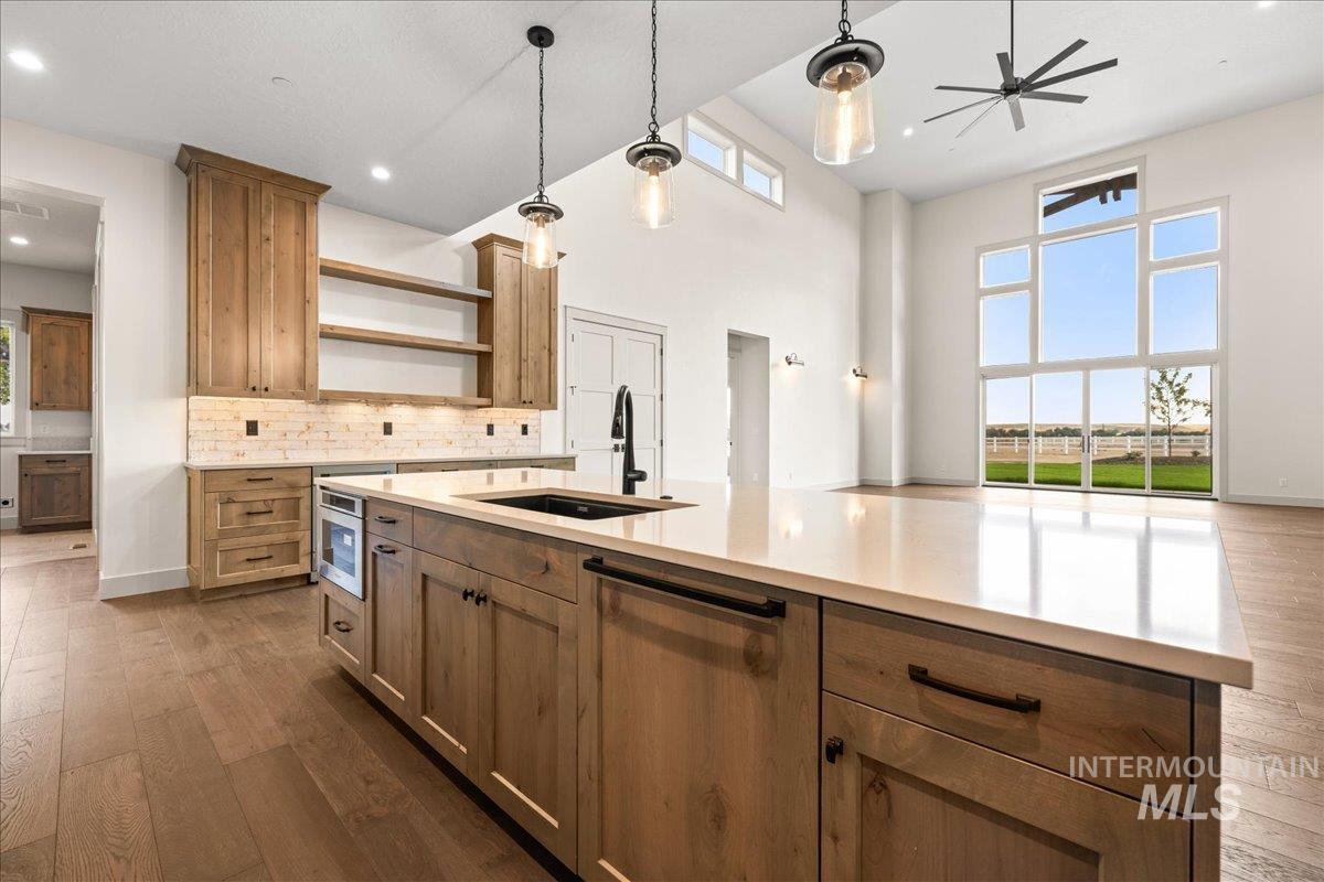 Kitchen with open shelves, dark wood finished floors, backsplash, pendant lighting, and brown cabinets