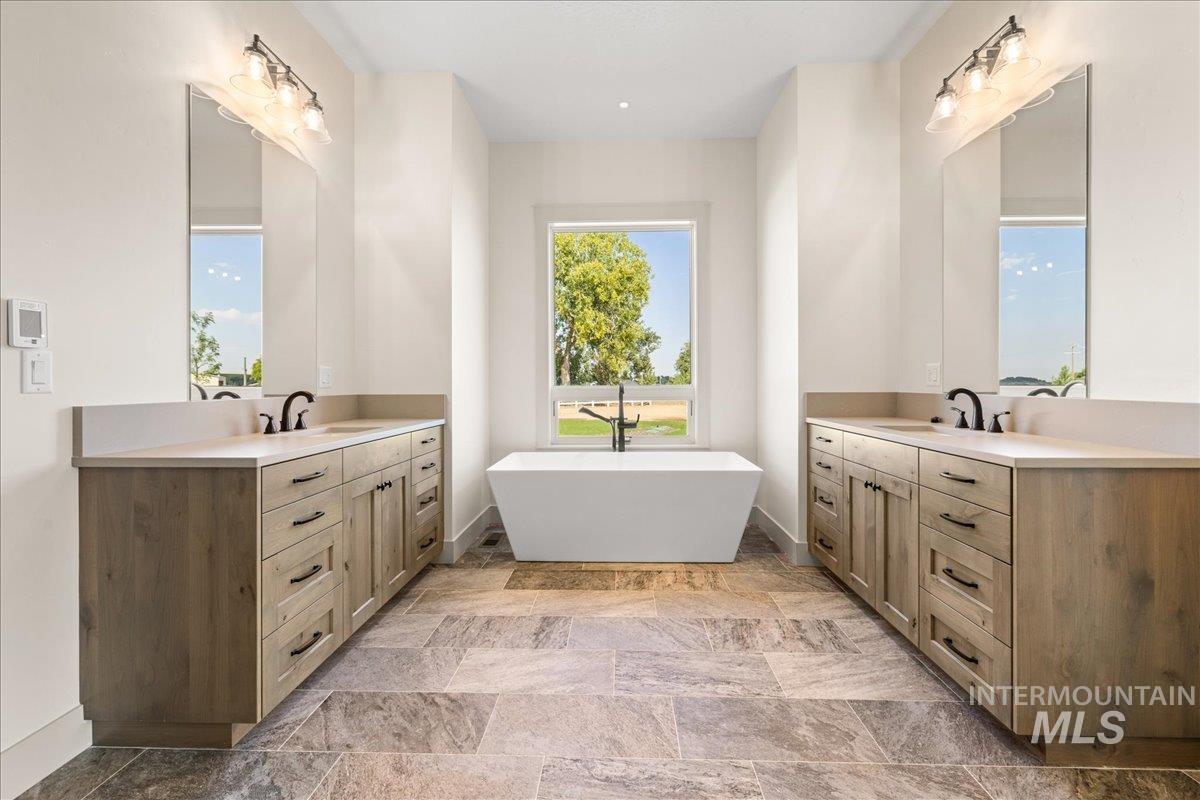 Bathroom with two vanities, a soaking tub, and plenty of natural light