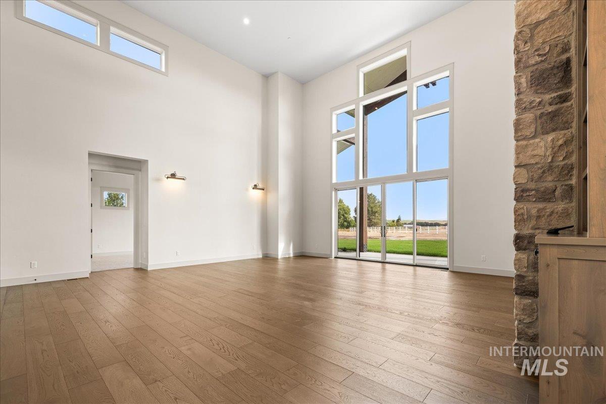 Unfurnished living room featuring a high ceiling and light wood-style flooring