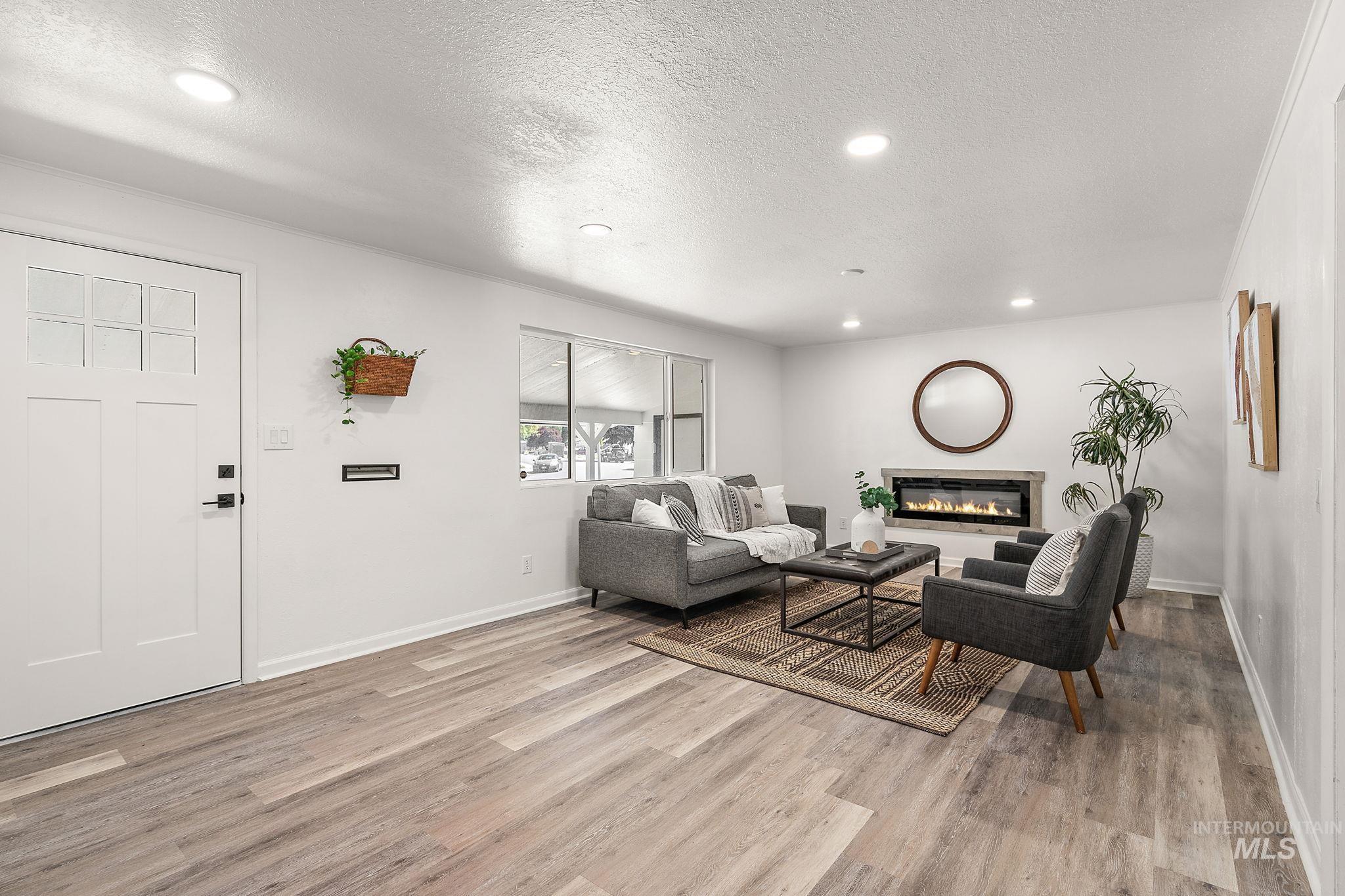 Living area featuring a glass covered fireplace, a textured ceiling, recessed lighting, and light wood-style floors