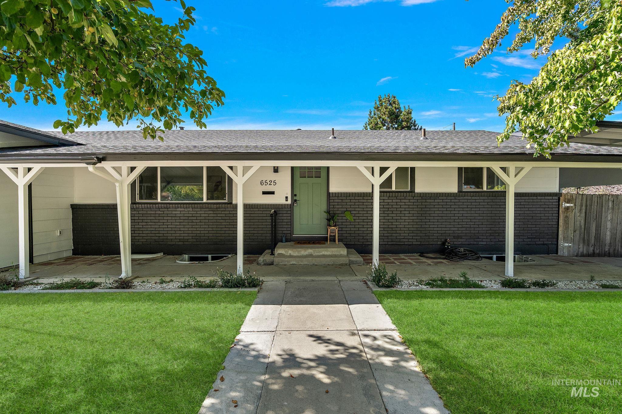 View of front of home with brick siding, a front yard, a shingled roof, and covered porch
