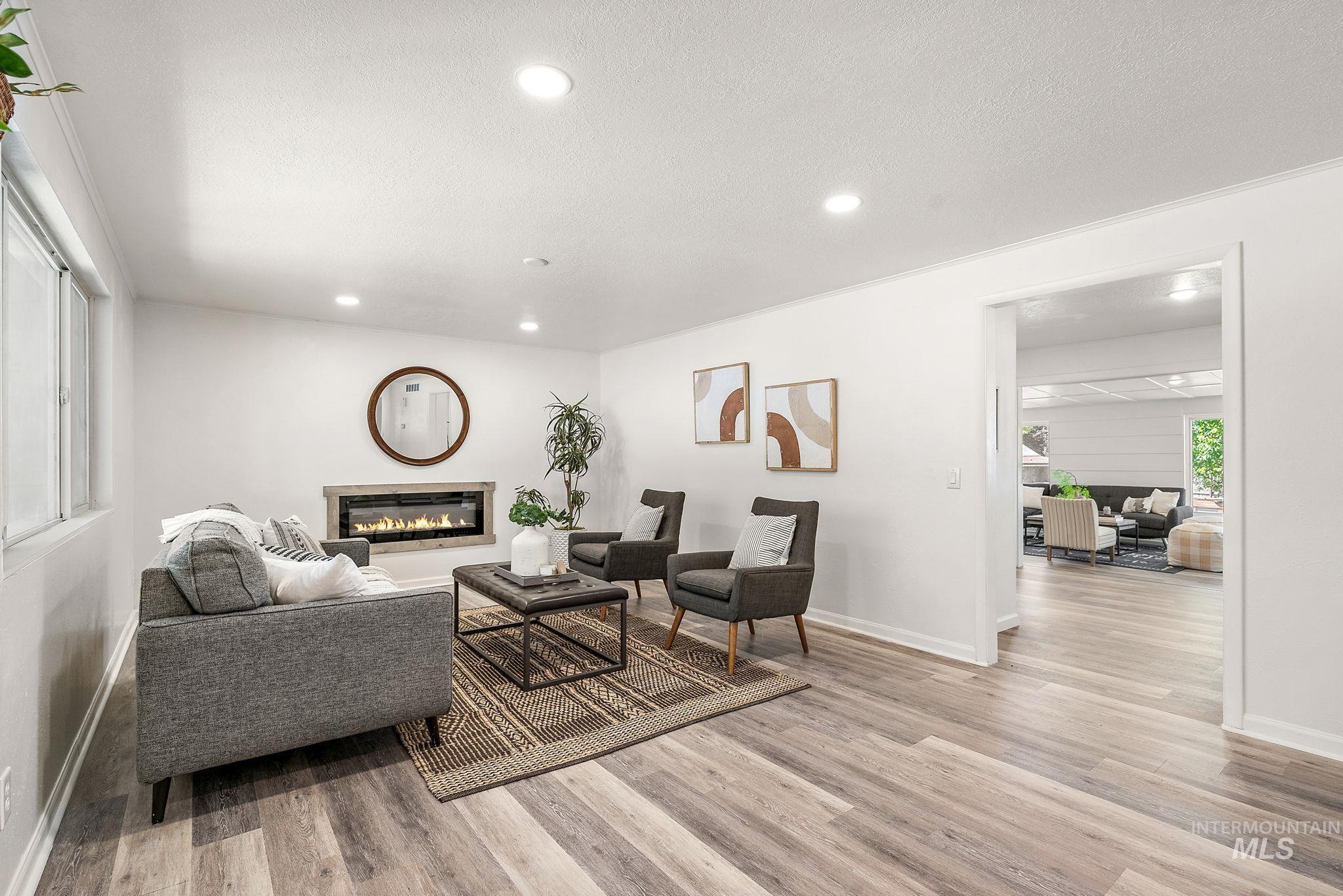 Living area with a glass covered fireplace, light wood-type flooring, recessed lighting, and a textured ceiling