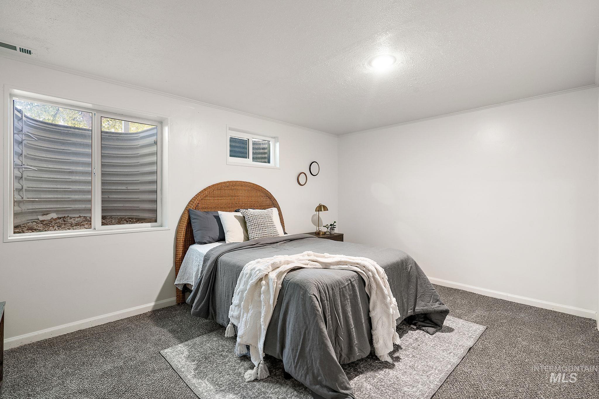 Carpeted bedroom with a textured ceiling and ornamental molding